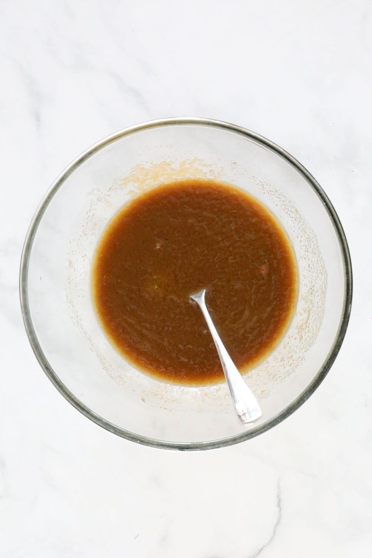 Brown sugar and caster sugar stirred into melted butter in a bowl.