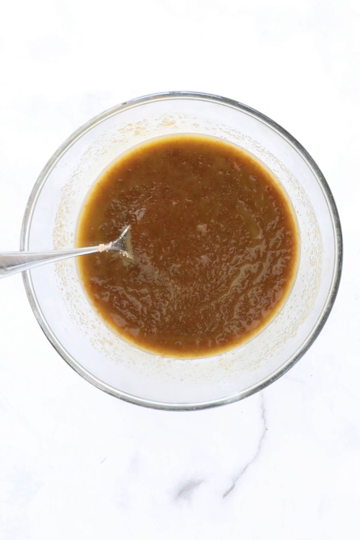 The mixed melted butter and brown sugar in a glass mixing bowl.