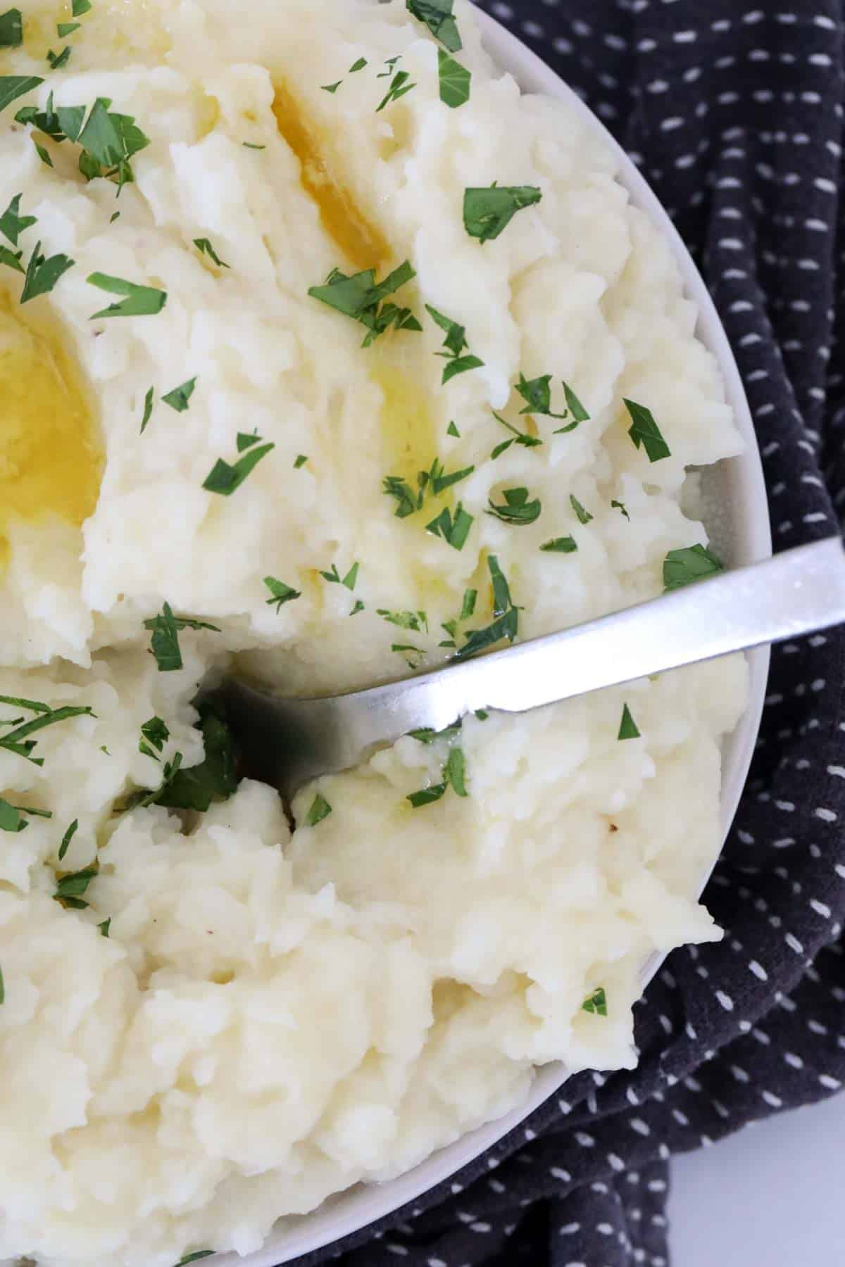 Mash in a serving bowl topped with melted butter and fresh parsley.