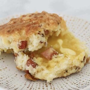 A halved warm bacon and cheese scone with melted butter.