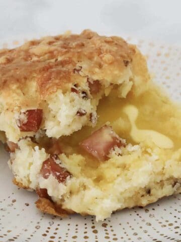 A halved warm bacon and cheese scone with melted butter.