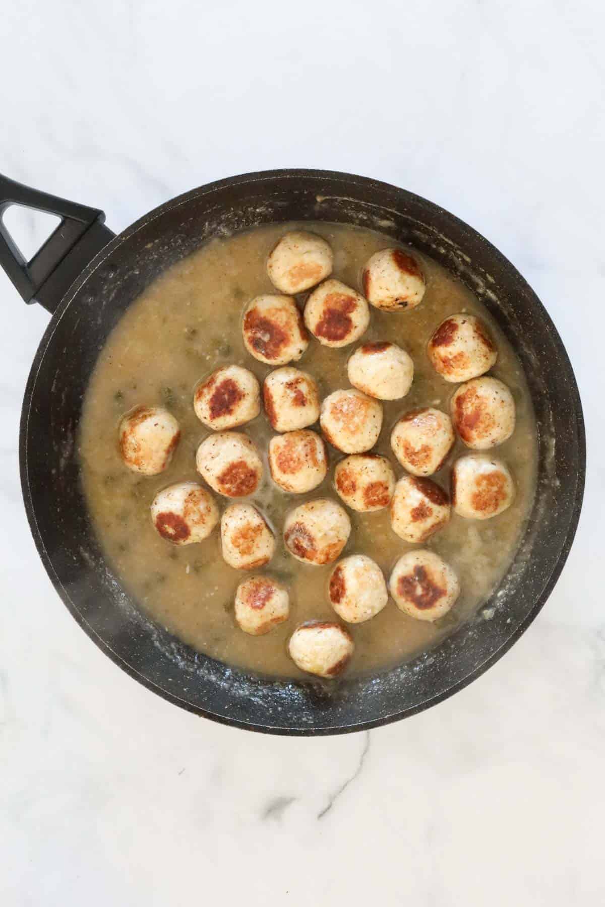 The chicken meatballs returned to the pan to finish cooking in the sauce.