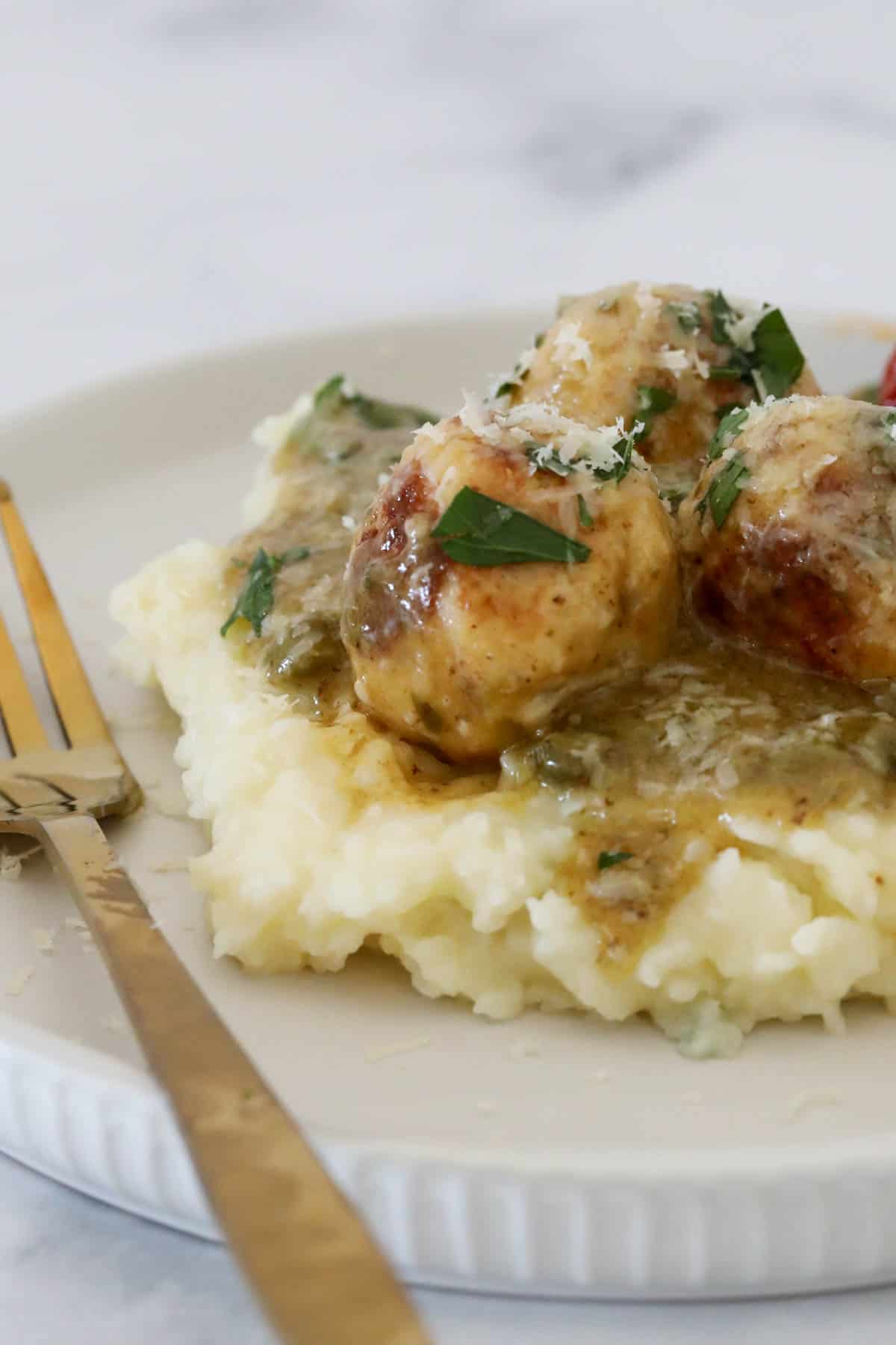 Meatballs in a lemon and caper sauce on a bed of mashed potato.