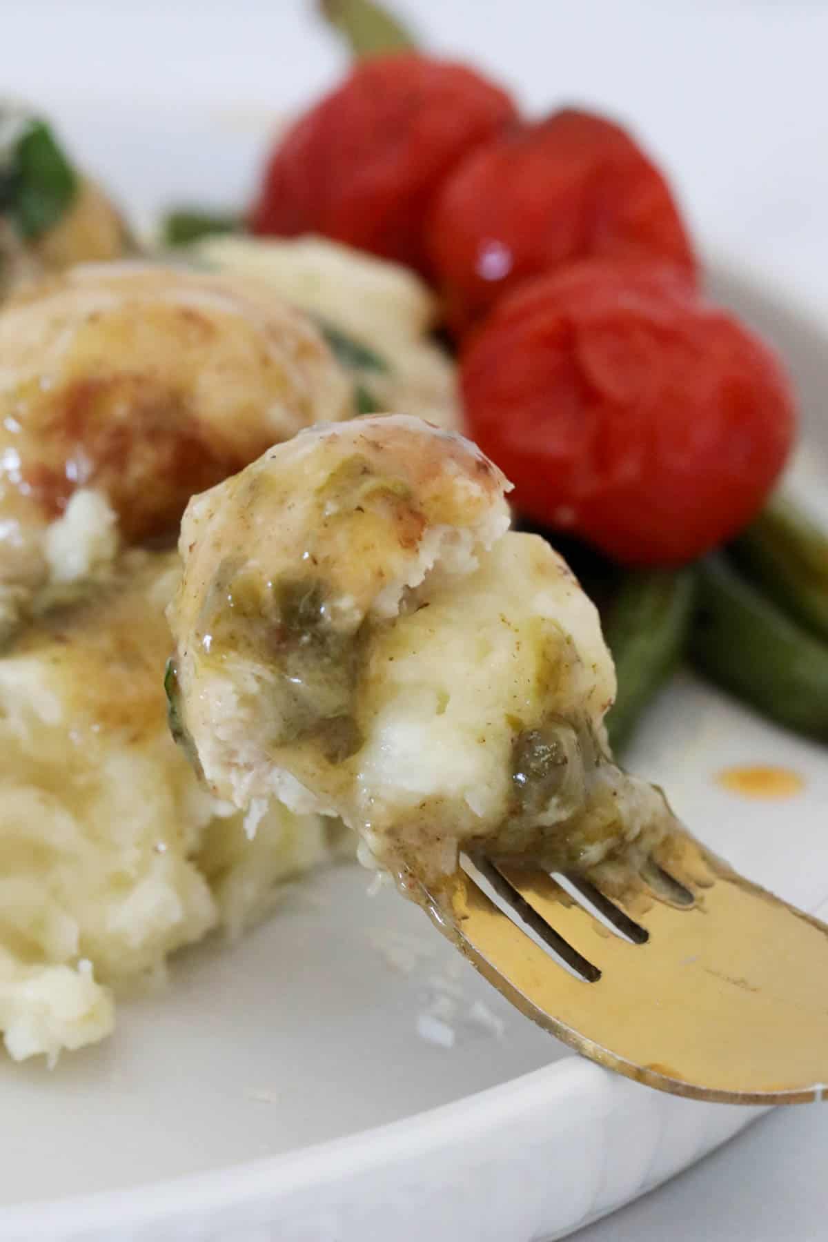 A fork holding up a mouthful of chicken piccata meatball.