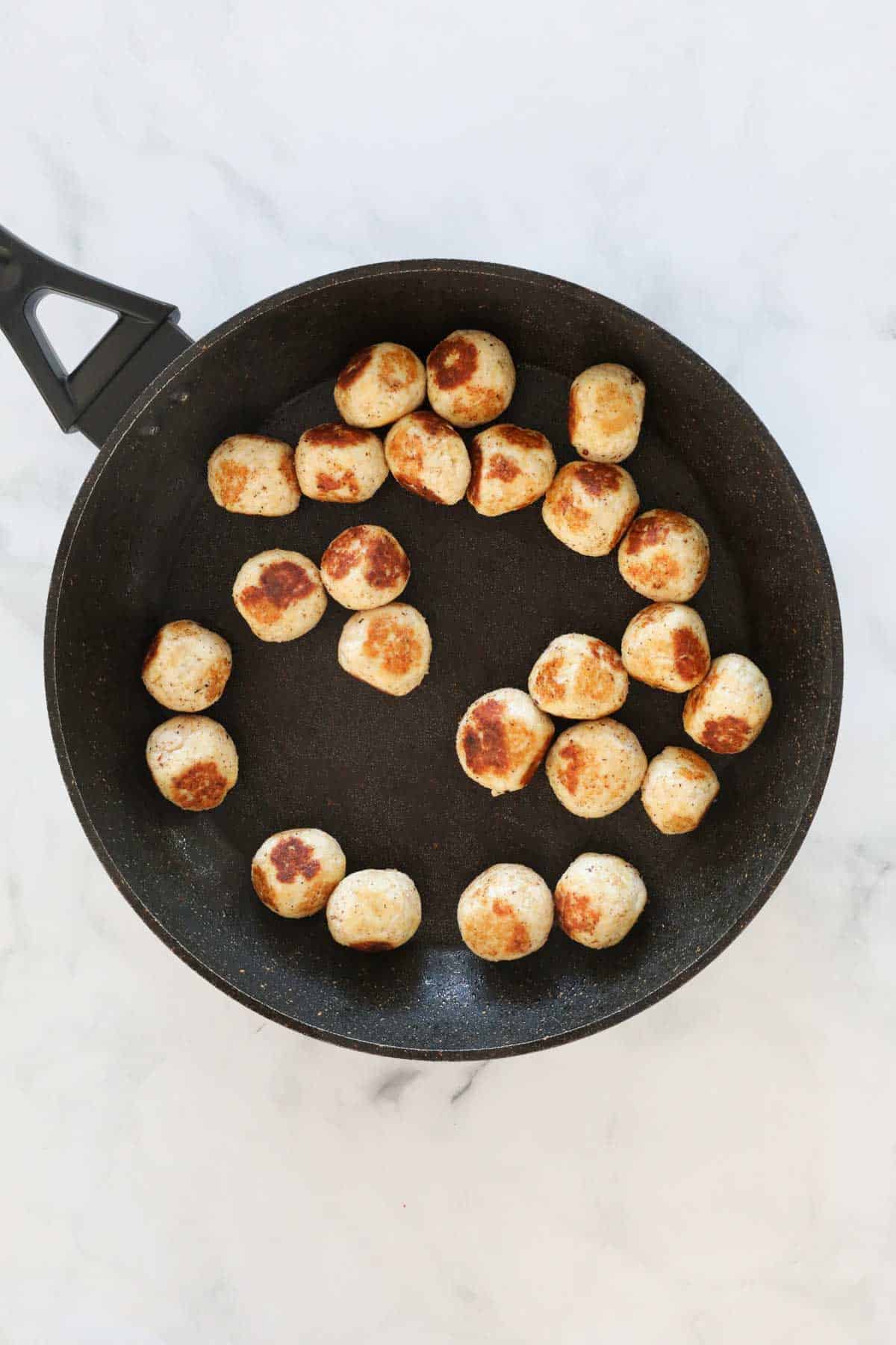 The fried chicken meatballs in a frying pan.