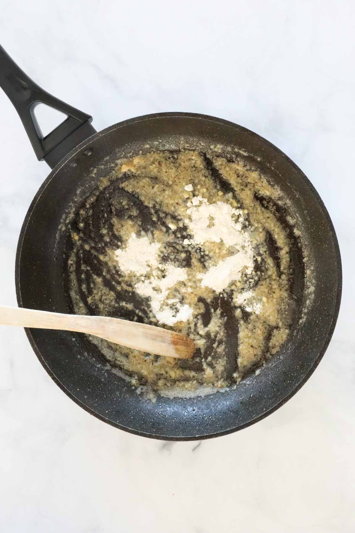 Flour being stirred in to the melted butter in the frying pan.