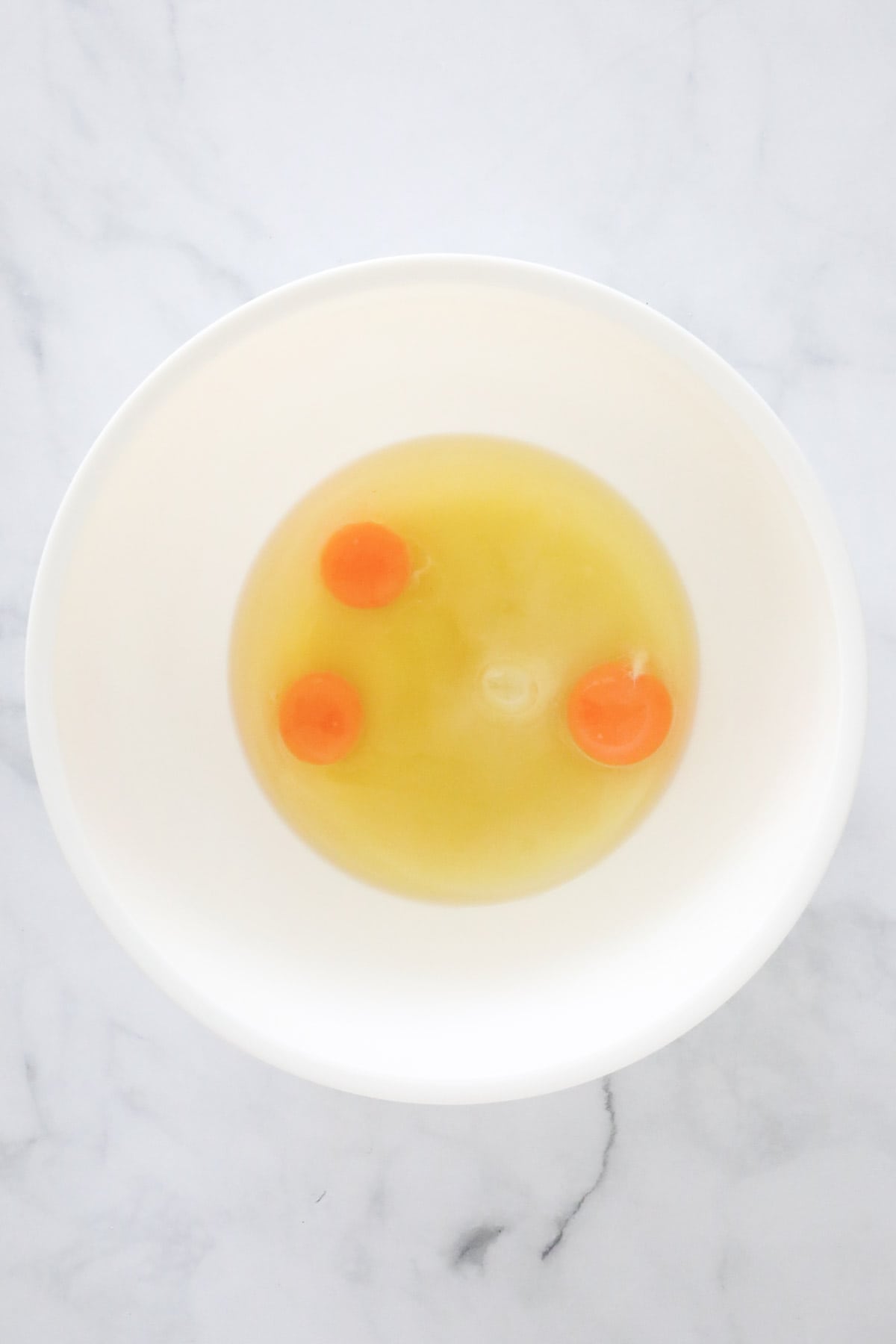 Eggs, caster sugar and olive oil placed in a bowl.