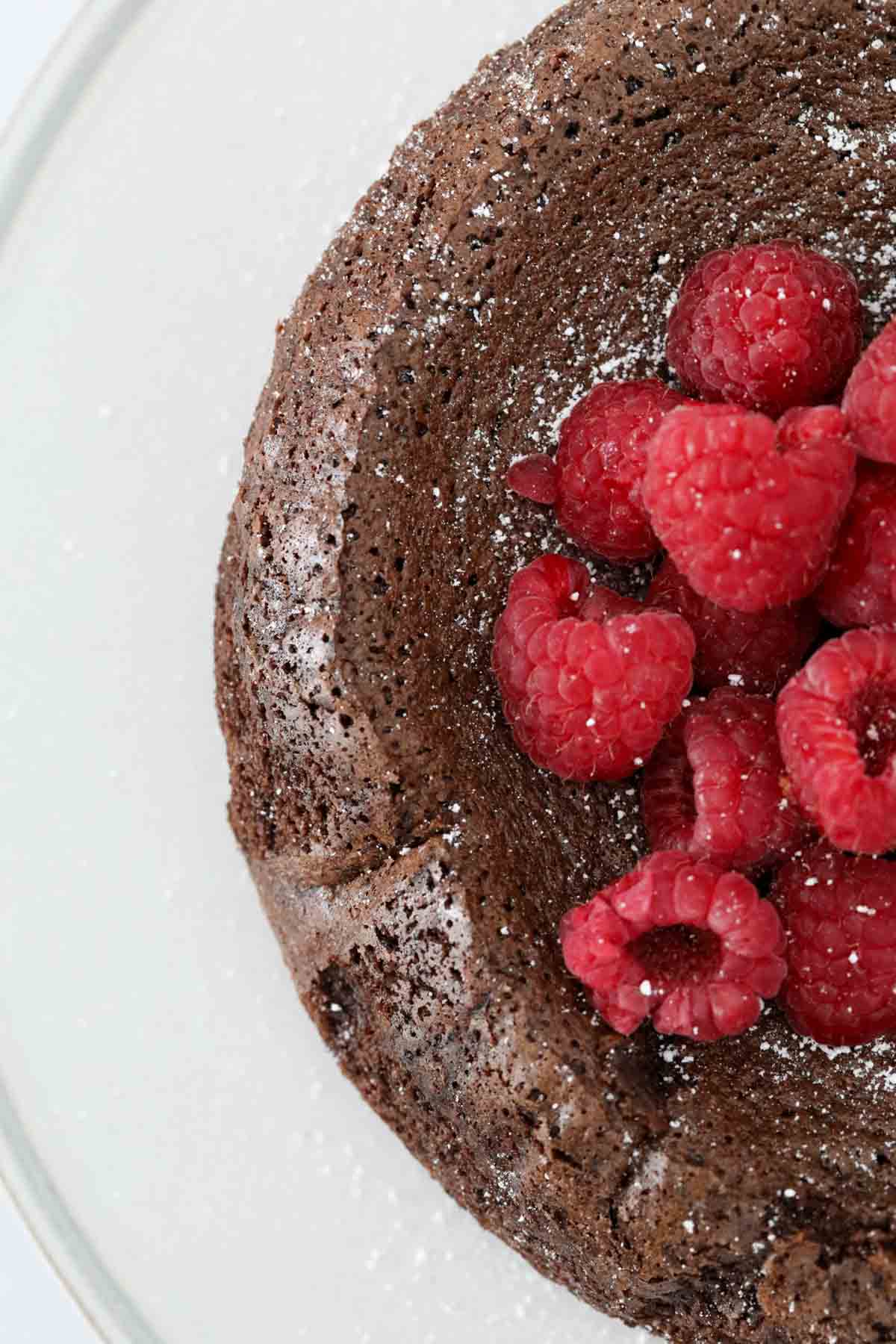 Looking down on a portion of a chocolate olive oil cake with raspberries on top.