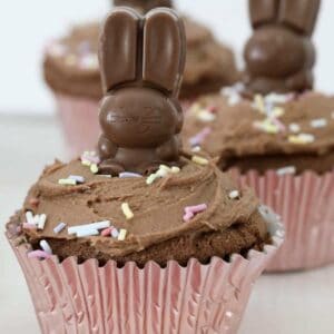 A chocolate cupcake topped with chocolate buttercream, a Easter bunny and sprinkles.
