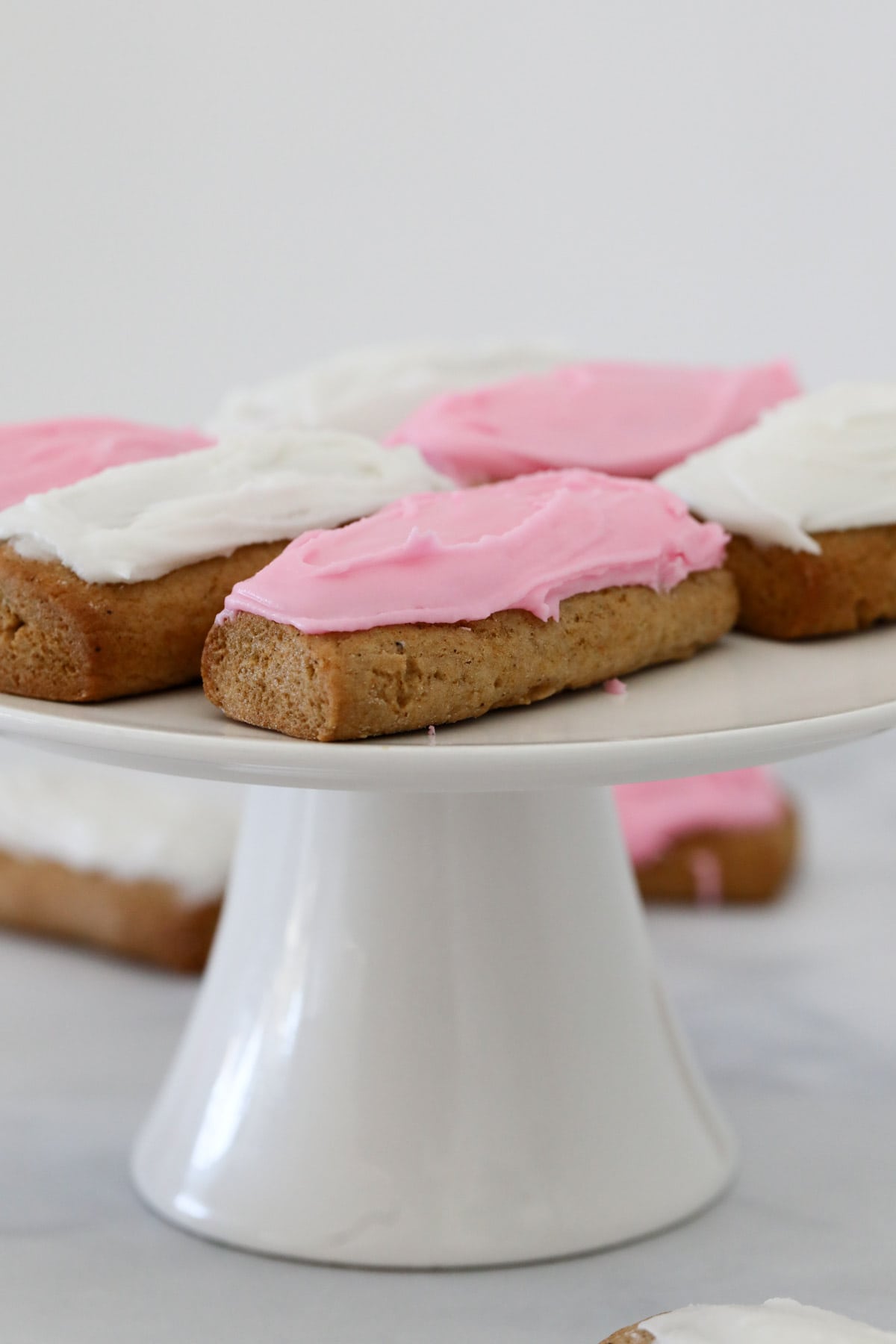 Iced honey jumbles on a white cake stand.