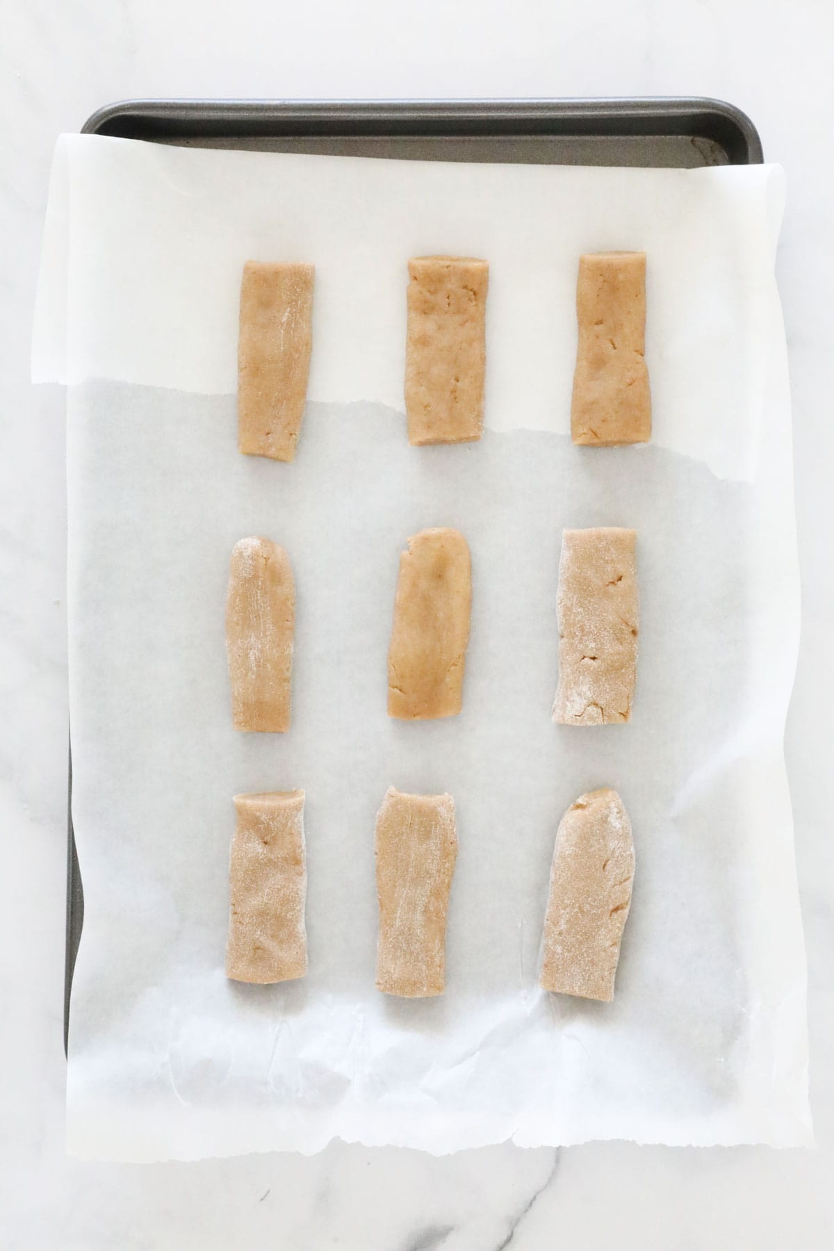 The pieces of cookie dough on a lined baking sheet.