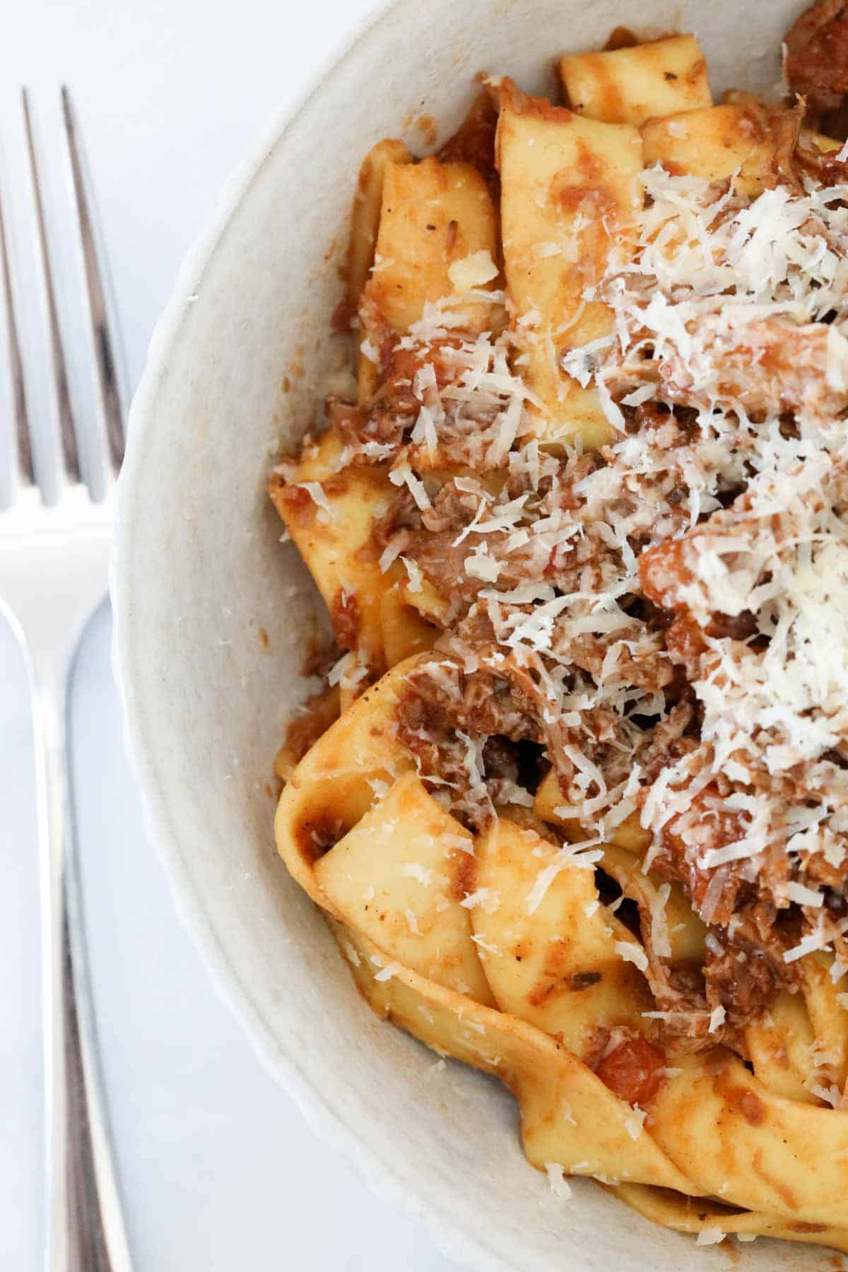 Lamb ragu and pappardelle in a bowl with a fork to the left side of the bowl.