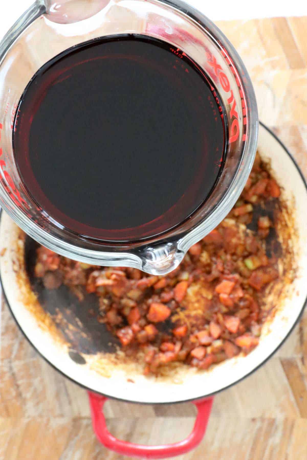 Red wine being poured in to the pan.