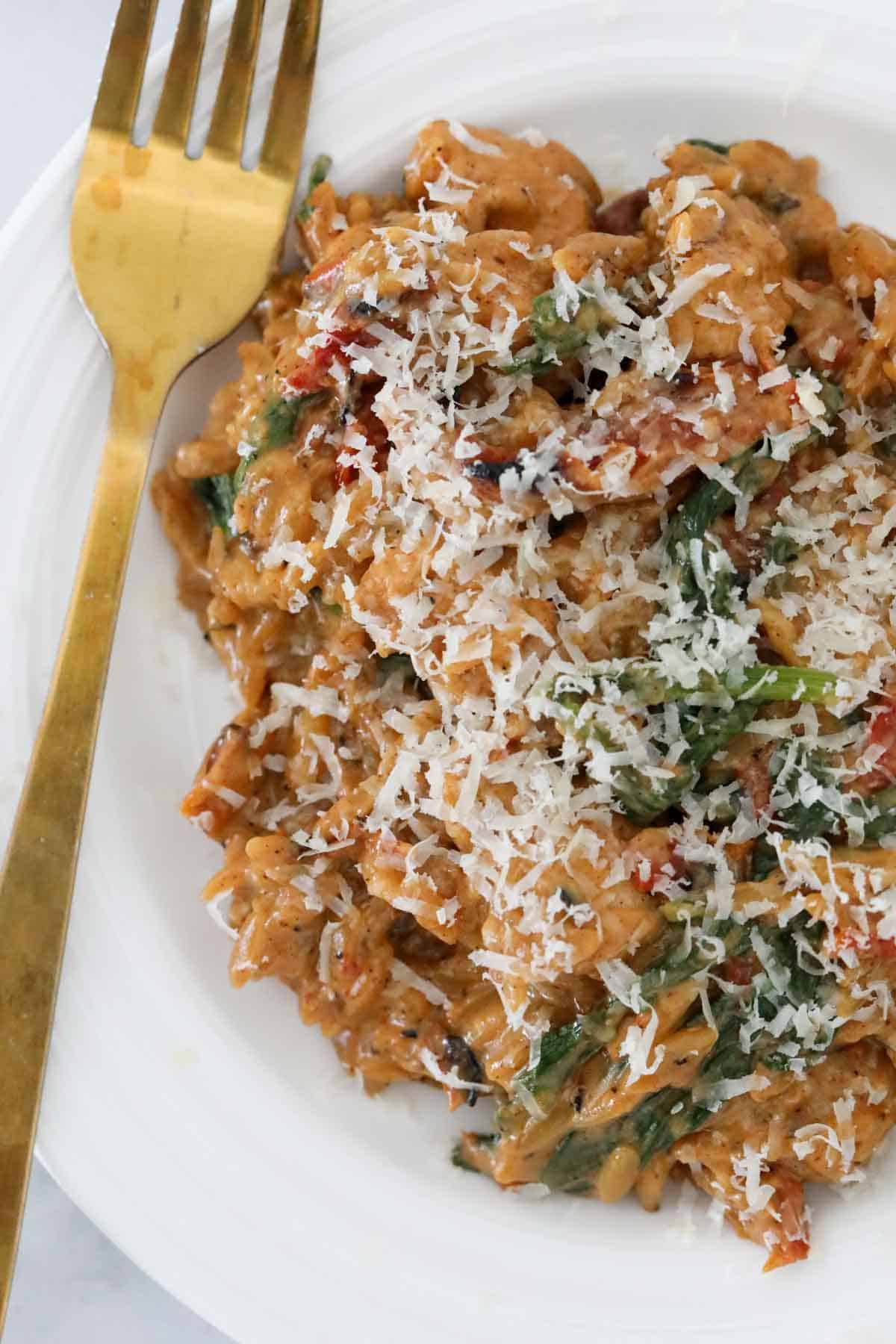 Marry me chicken pasta on a white plate sprinkled with grated parmesan.