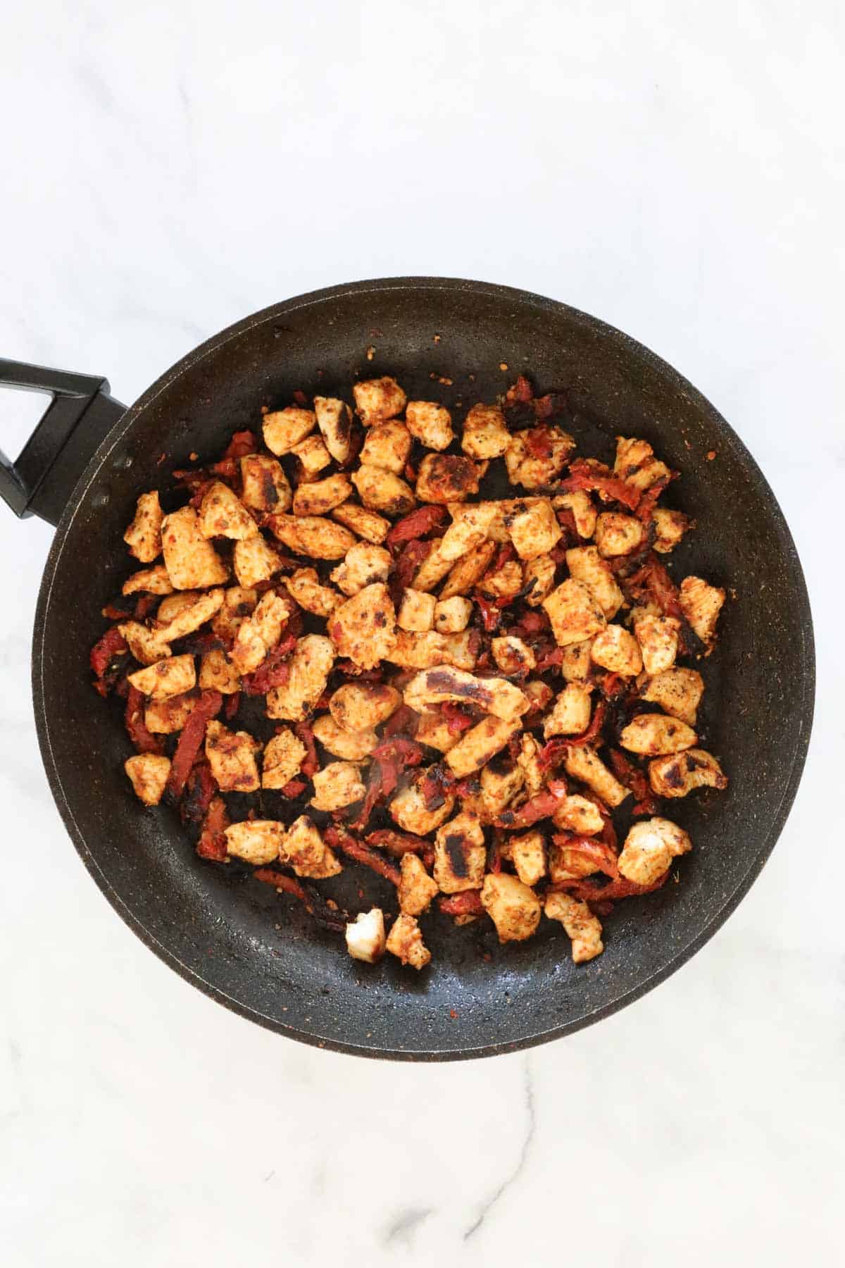 Garlic, sun dried tomatoes, paprika and oregano added to the chicken in the frying pan.