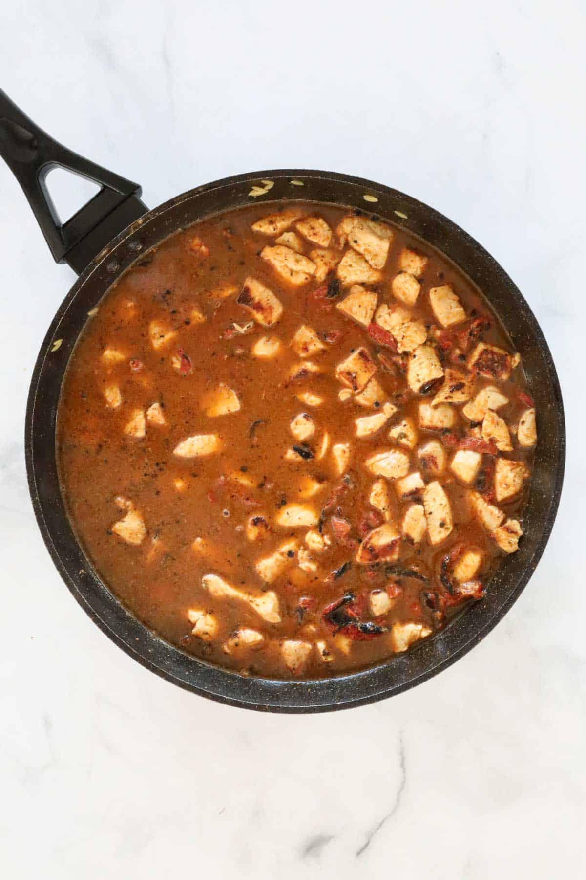 Risoni and chicken stock added to the pan.