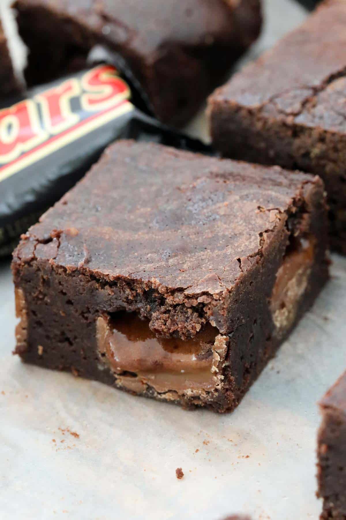 A close up of a square chocolate slice, in front of a Mars Bar.