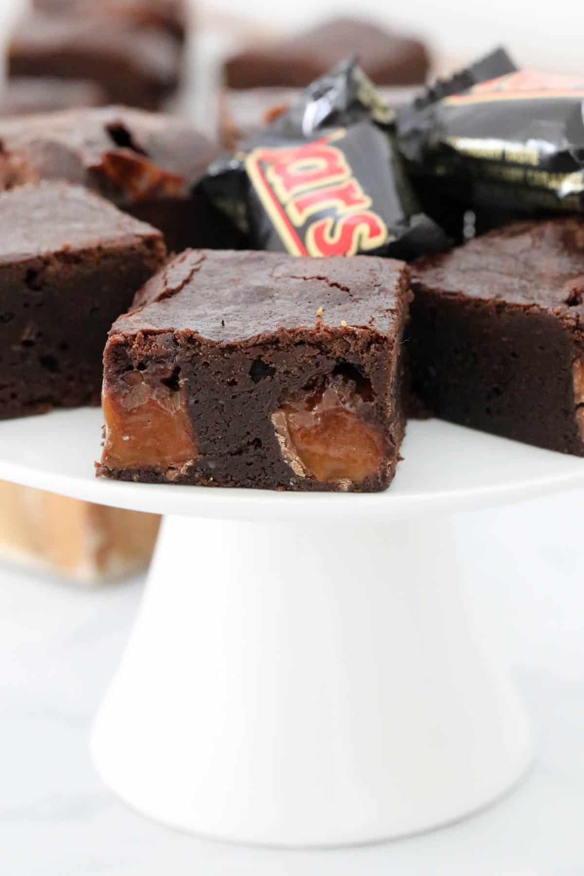 Dense fudgy brownie squares on a cake stand.