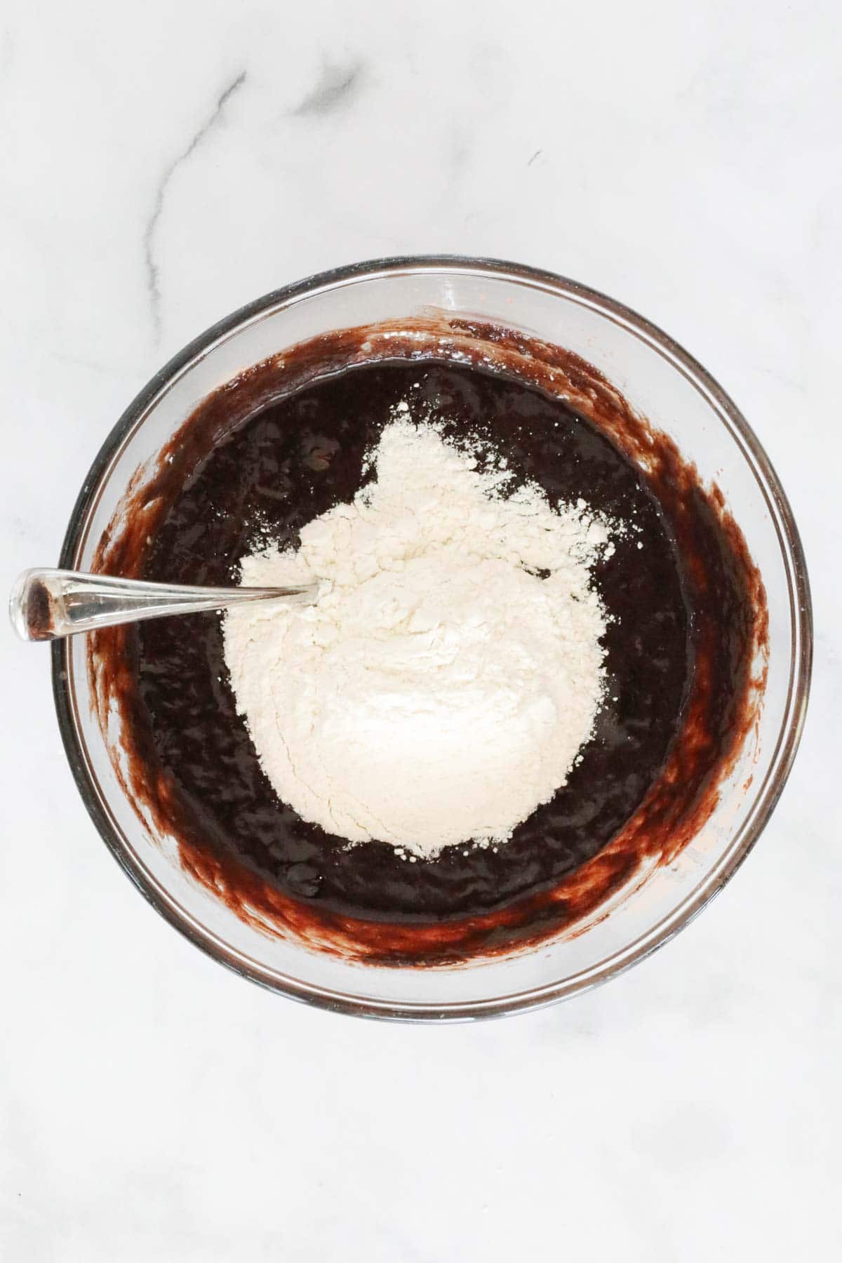 Flour sifted over the chocolate mixture in mixing bowl.