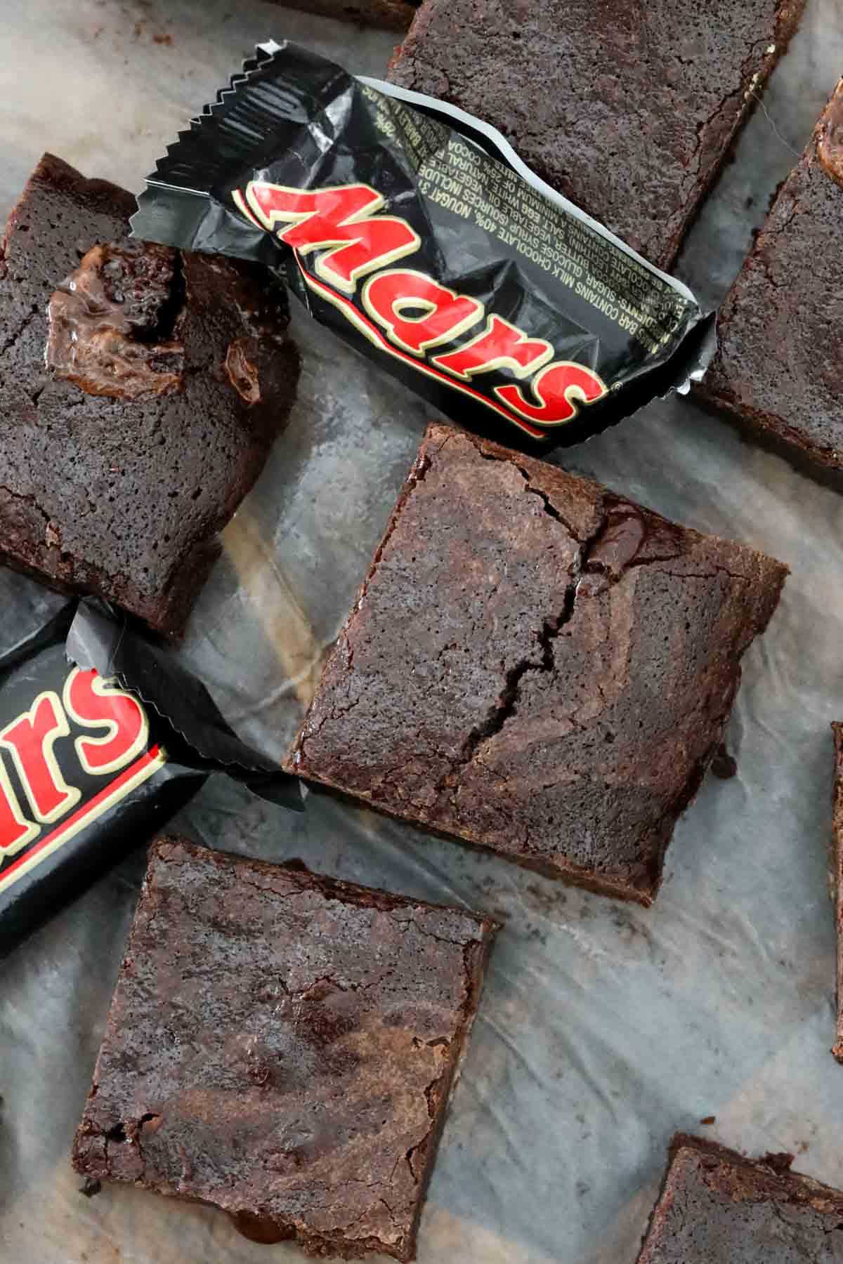 Looking down on little squares of chocolate brownie, with fun sized Mars Bars around them.