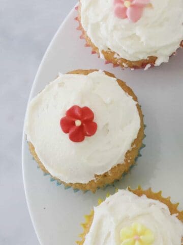 Little mini cupcakes topped with vanilla buttercream and decorative flowers.