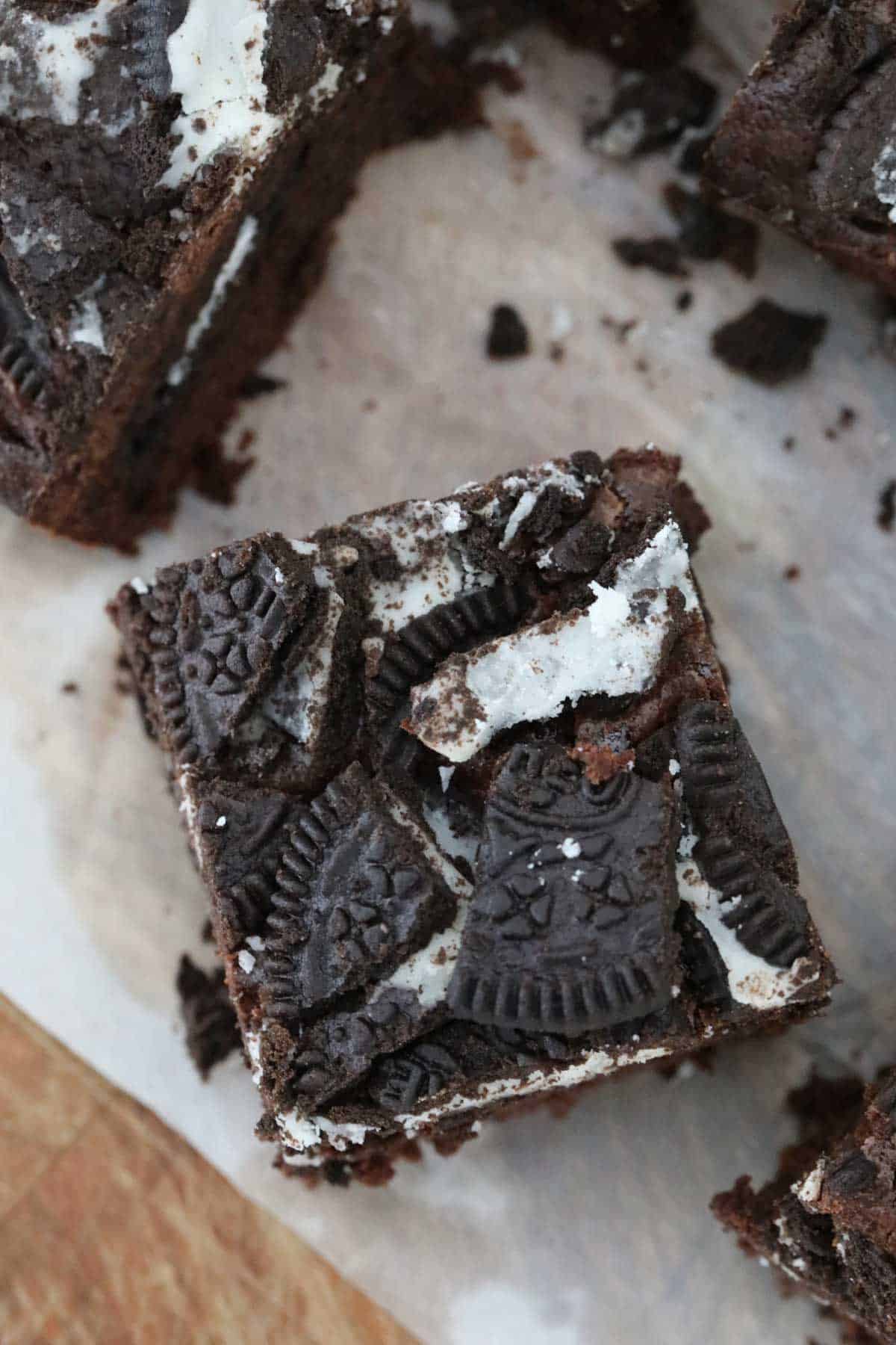 Close up of a square of freshly baked brownie with chunks of Oreo cookies on top.