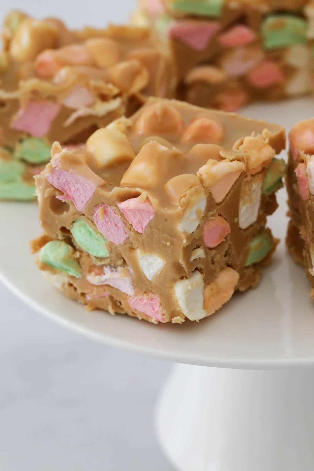 Close up of a peanut butter marshmallow square on a white cake stand.