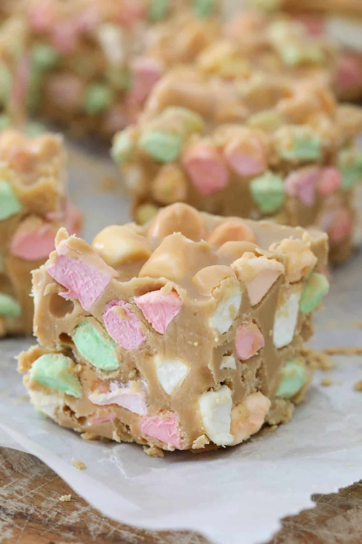 Close up of a cut peanut butter marshmallow square on white baking paper.