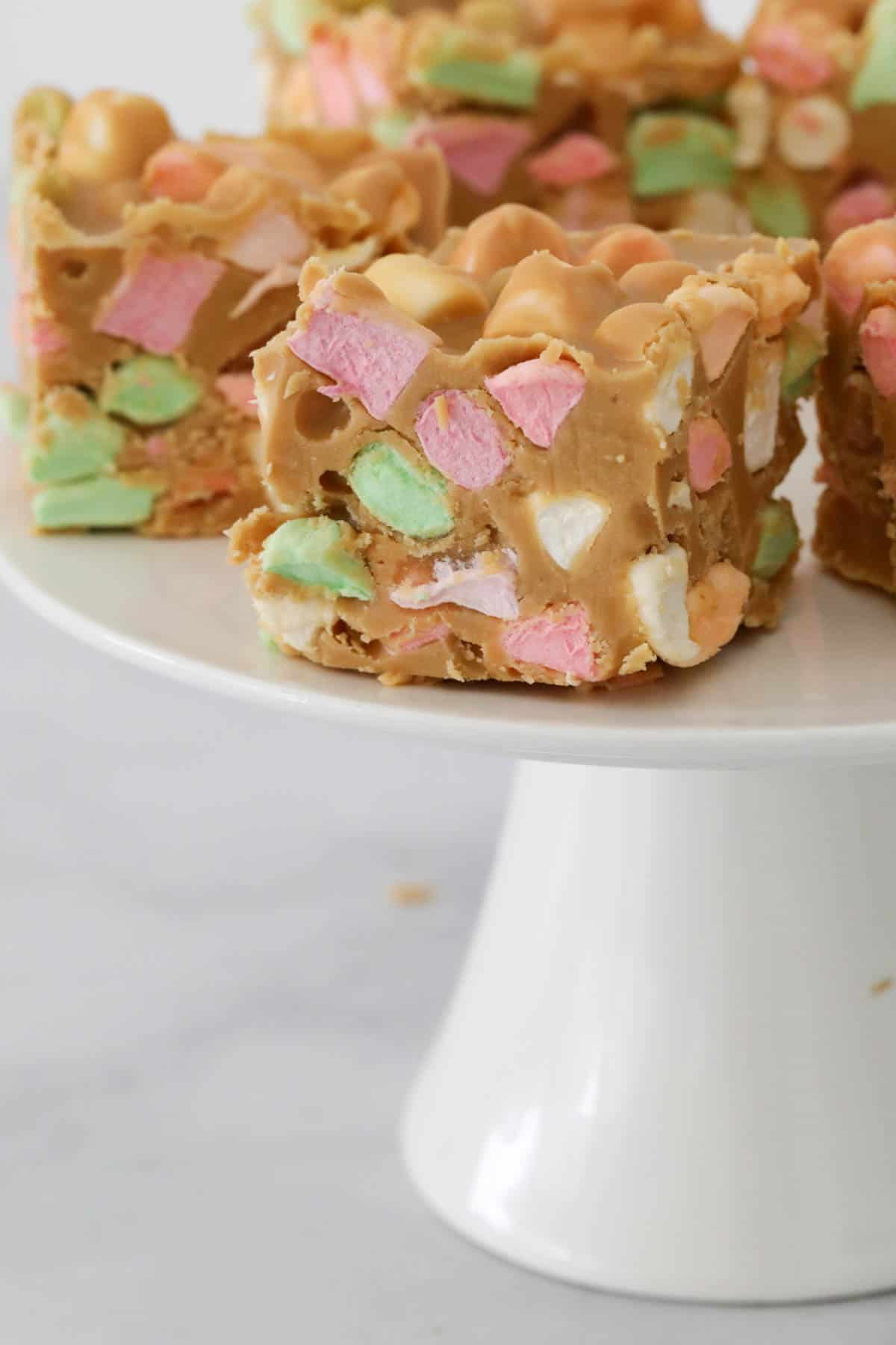 Confetti butterscotch squares on a white cake stand.