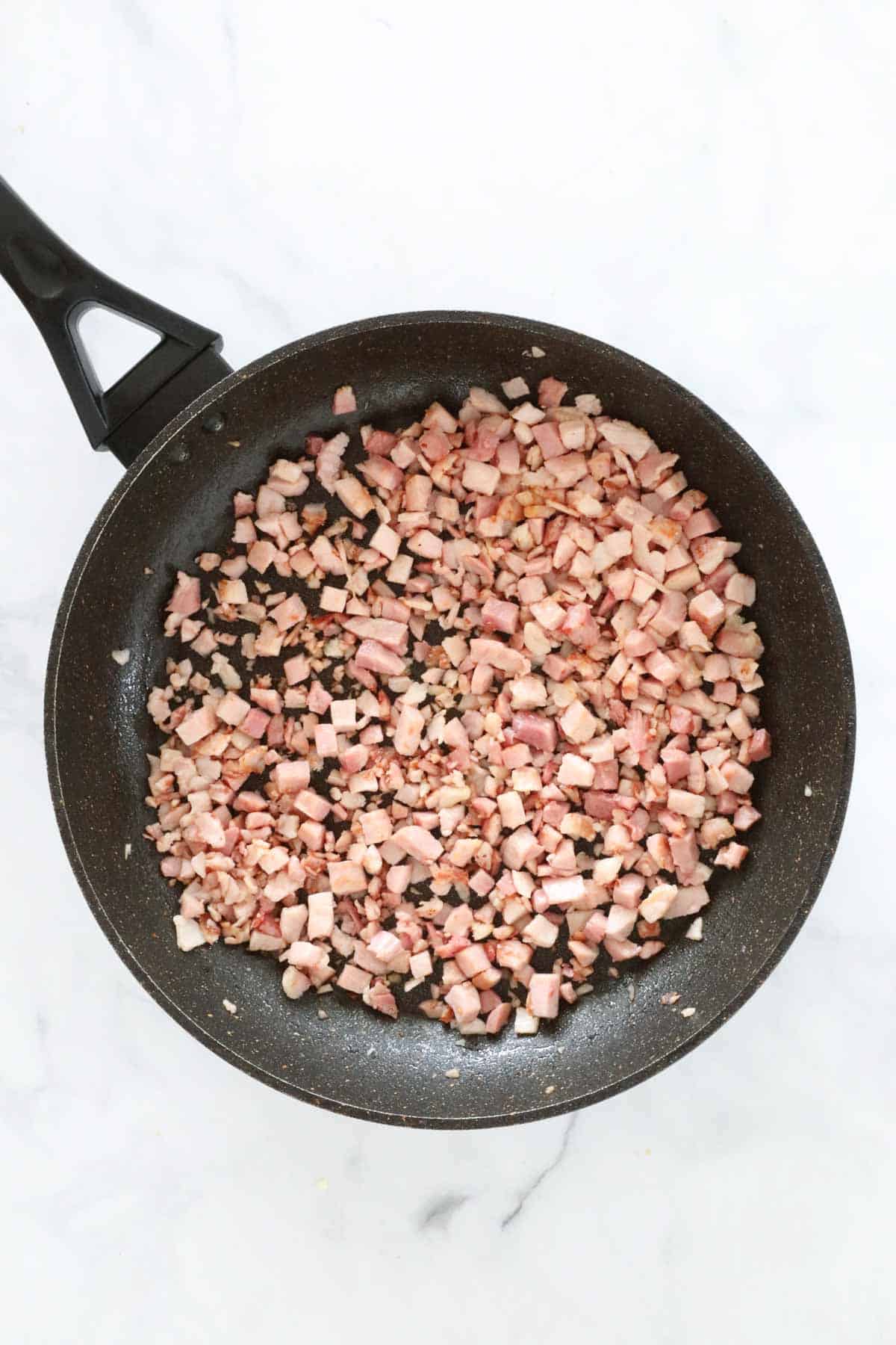 Bacon pieces in a frying pan.