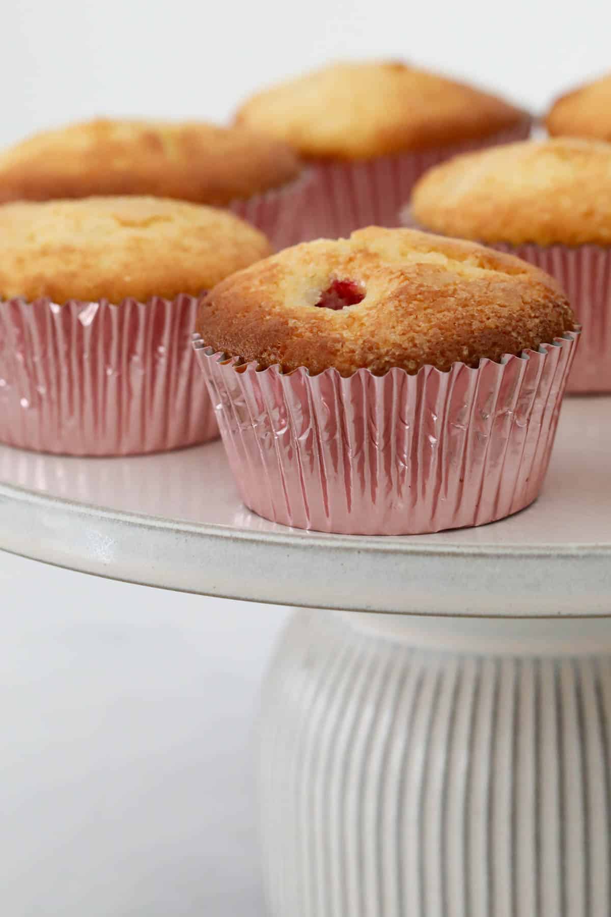 A batch of lemon and raspberry muffins on a cake stand.