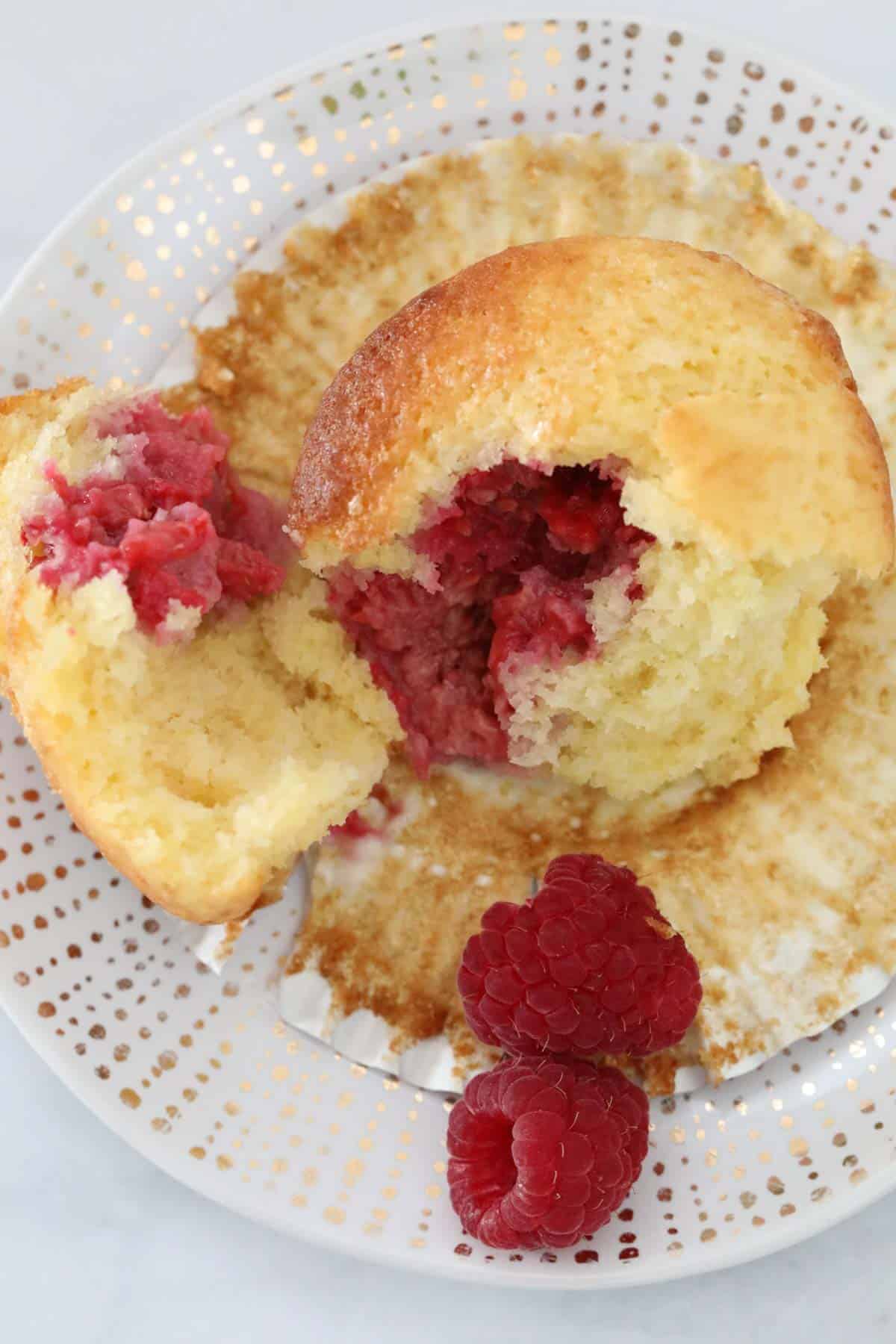 An overhead shot of a muffin split open showing the raspberries inside.