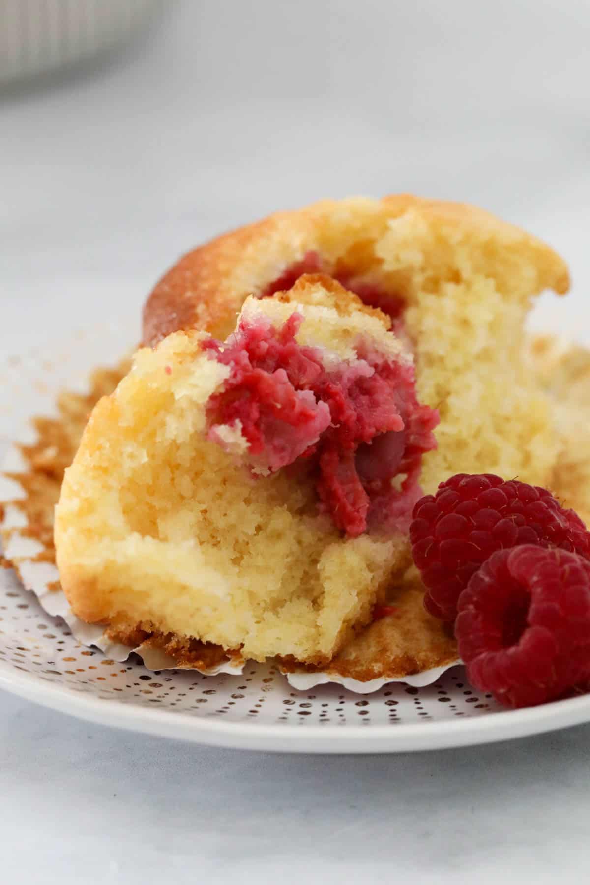 A muffin split open to show fresh raspberries inside.