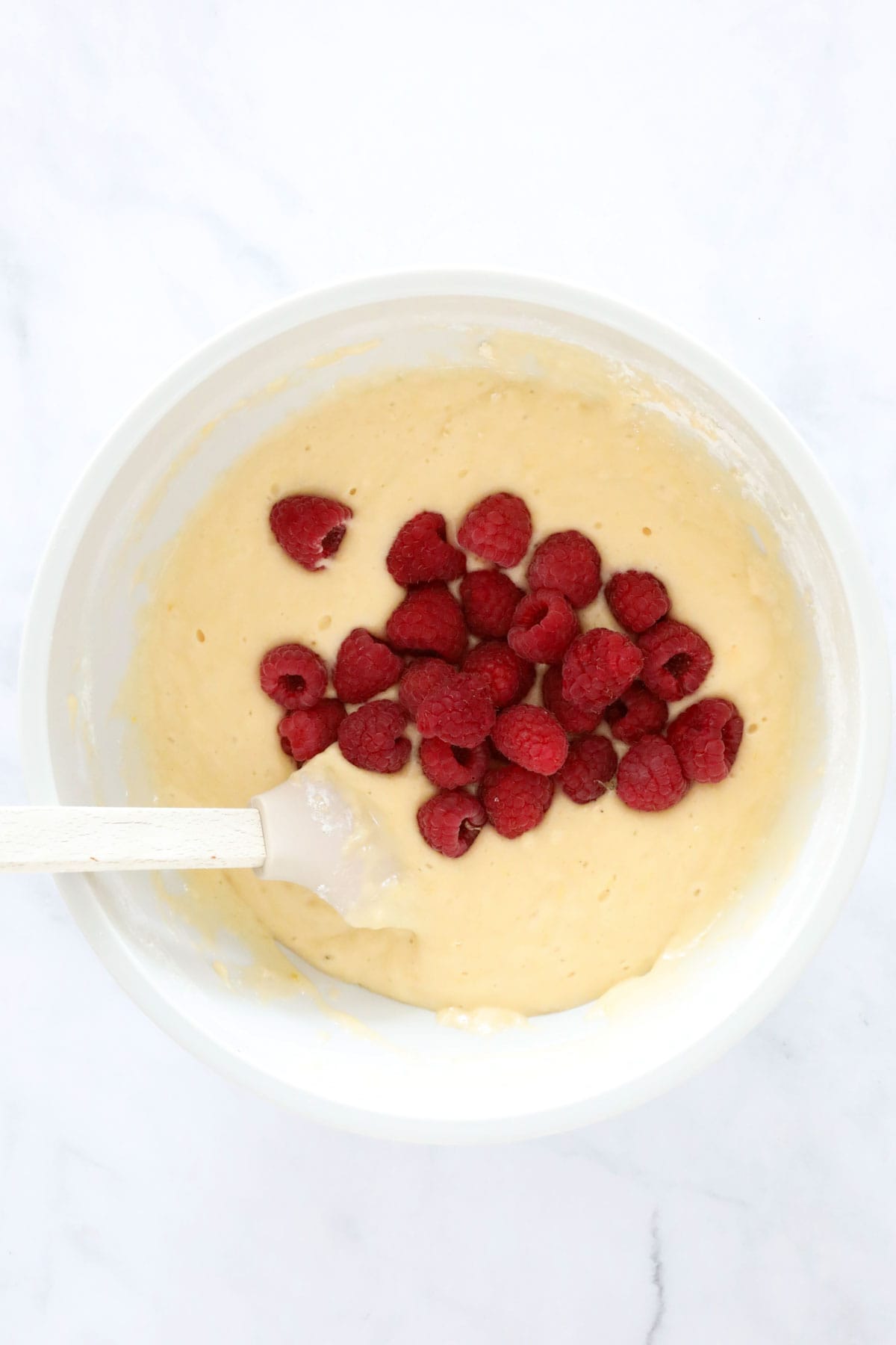 Raspberries added to the muffin batter in the mixing bowl.