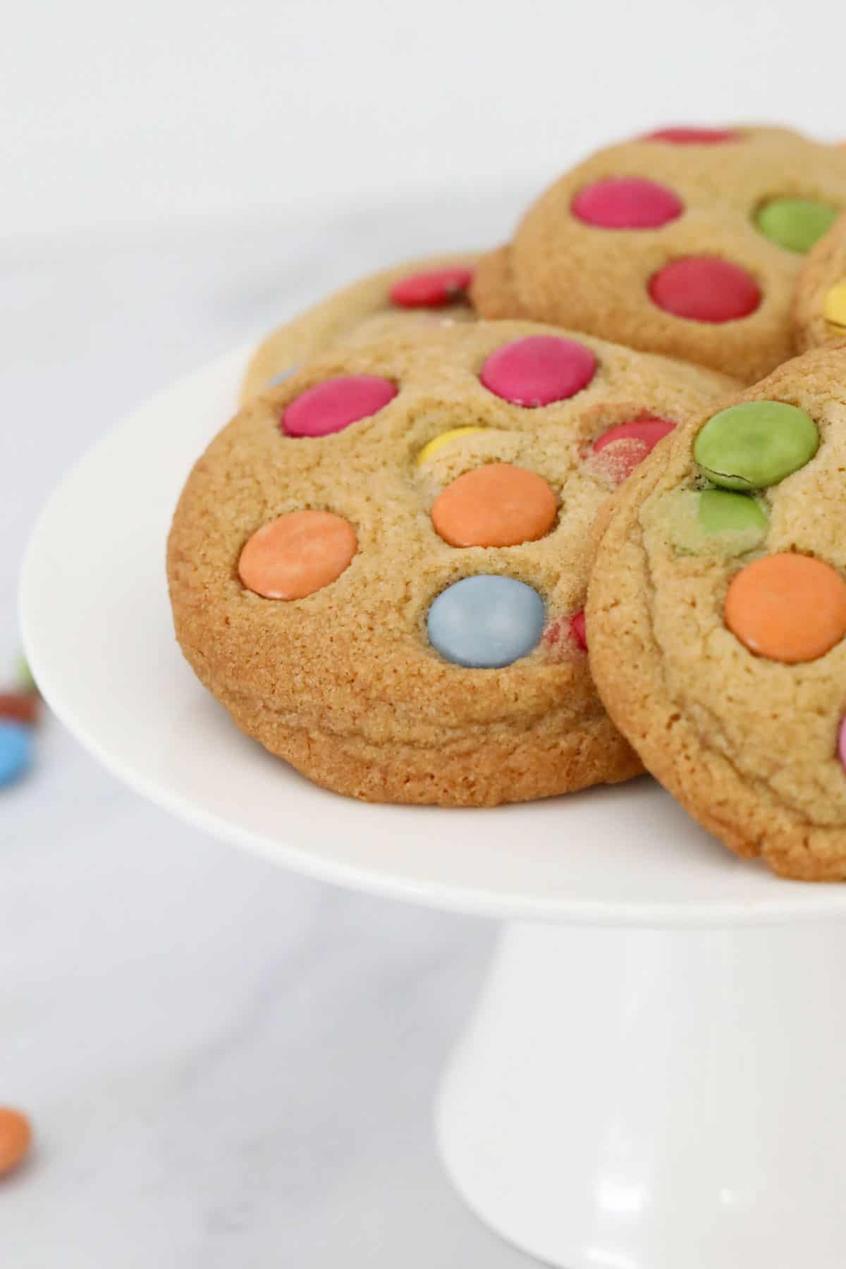 Smarties cookies on a white cake stand.