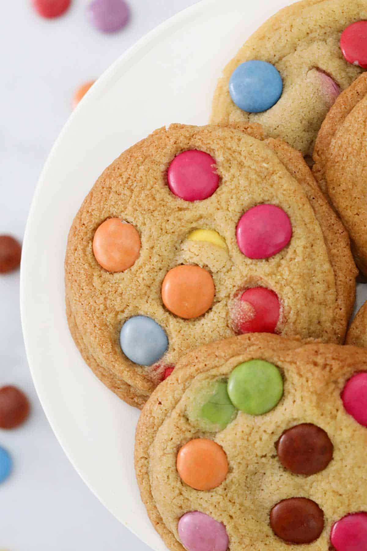 Overhead view of Smarties cookies on a white cake stand.