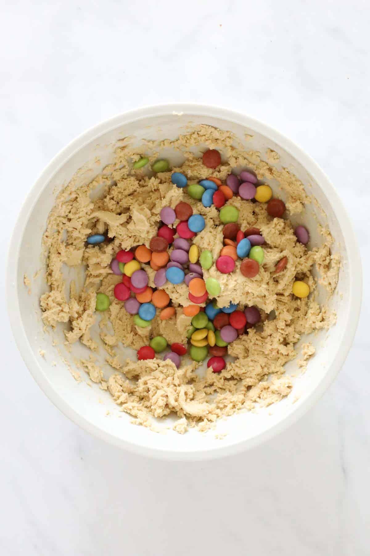 Smarties added to the cookie dough in the bowl.