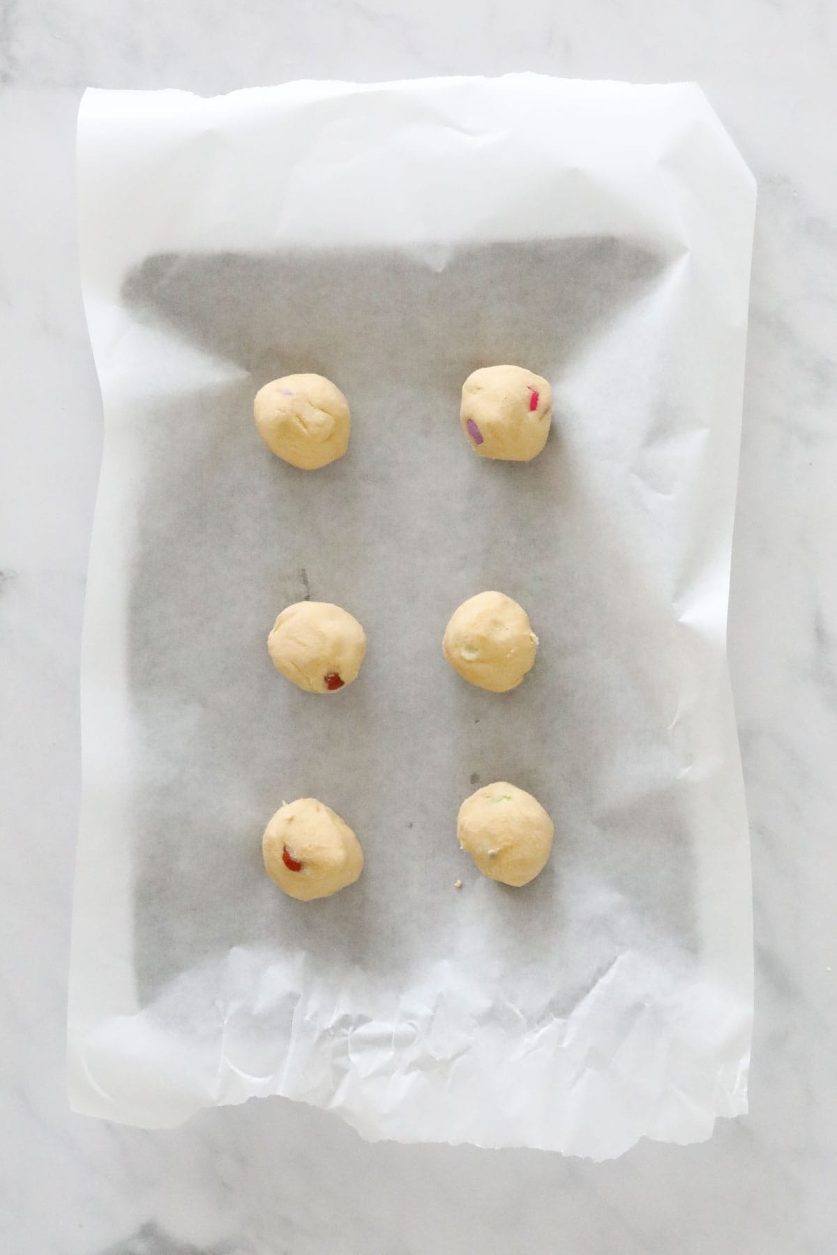 Balls of cookie dough on a lined baking tray.