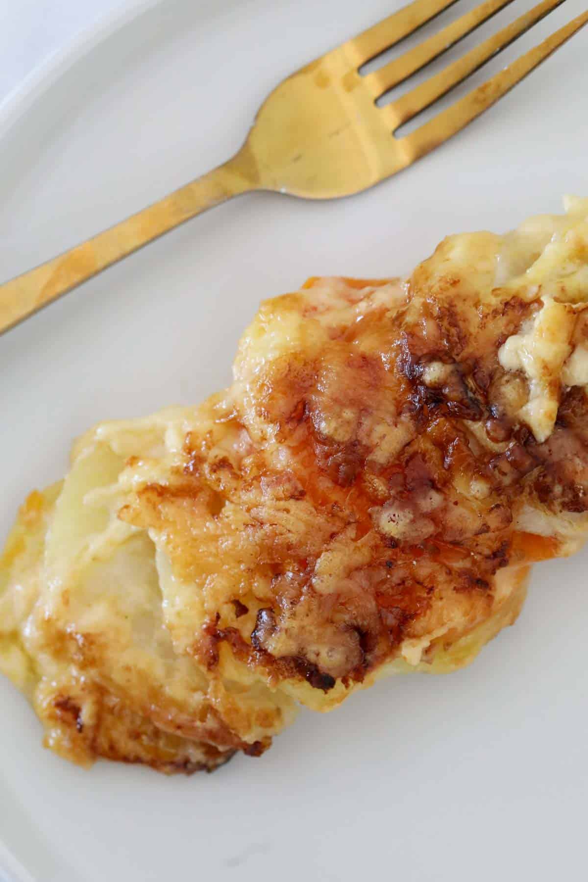 A portion of the vegetable gratin on a white plate with a fork next to it.