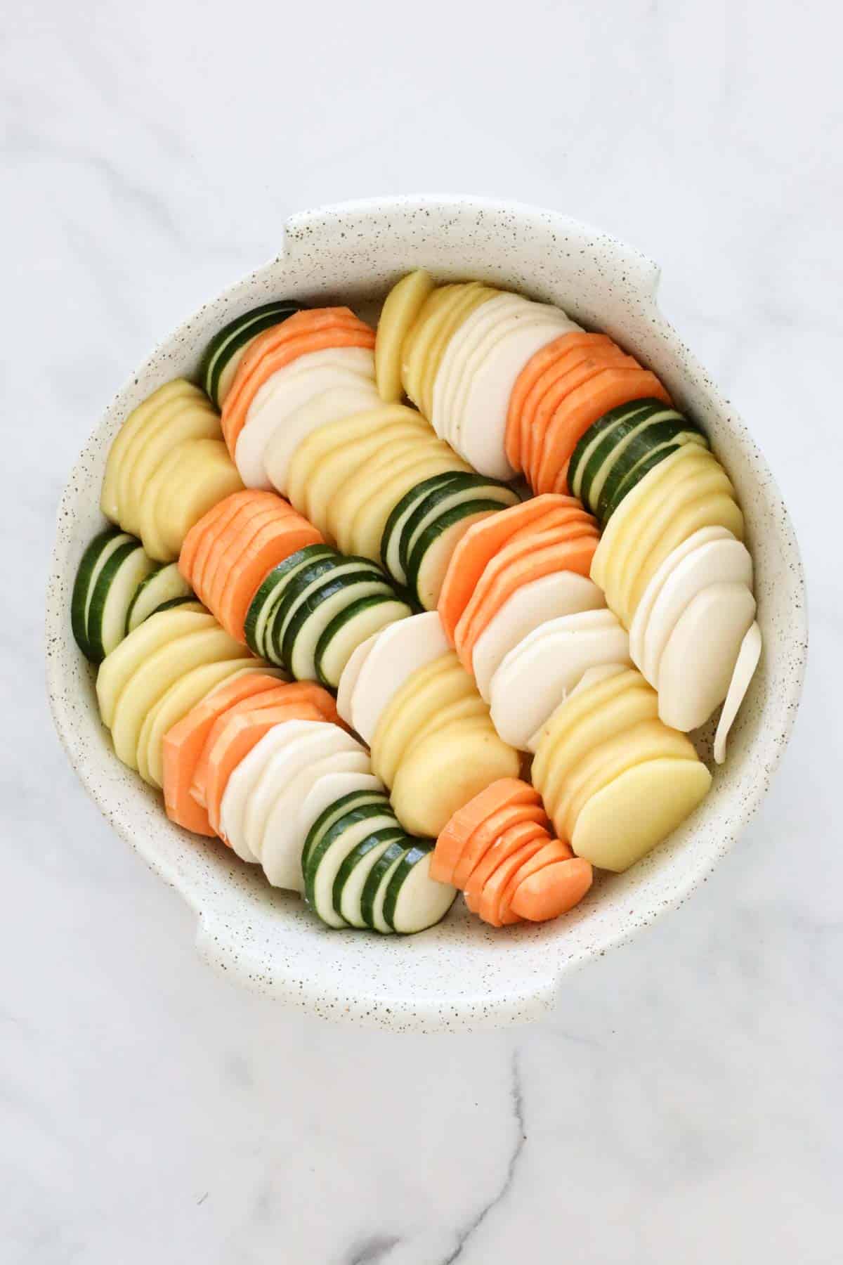 The sliced vegetables arranged in an ovenproof dish.