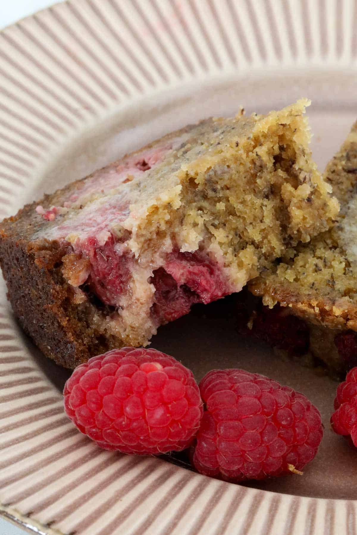 A buttered slice of raspberry banana bread with a bite taken out.