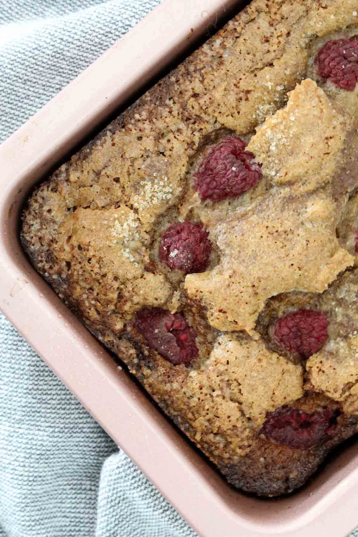 Overhead shot of raspberry banana bread in a pink baking tin.