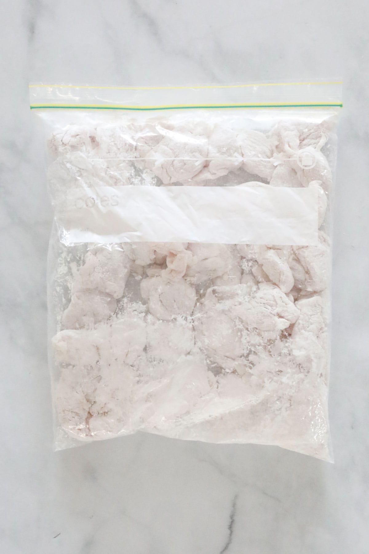 The chicken pieces tossed with cornstarch in a Ziplock bag.