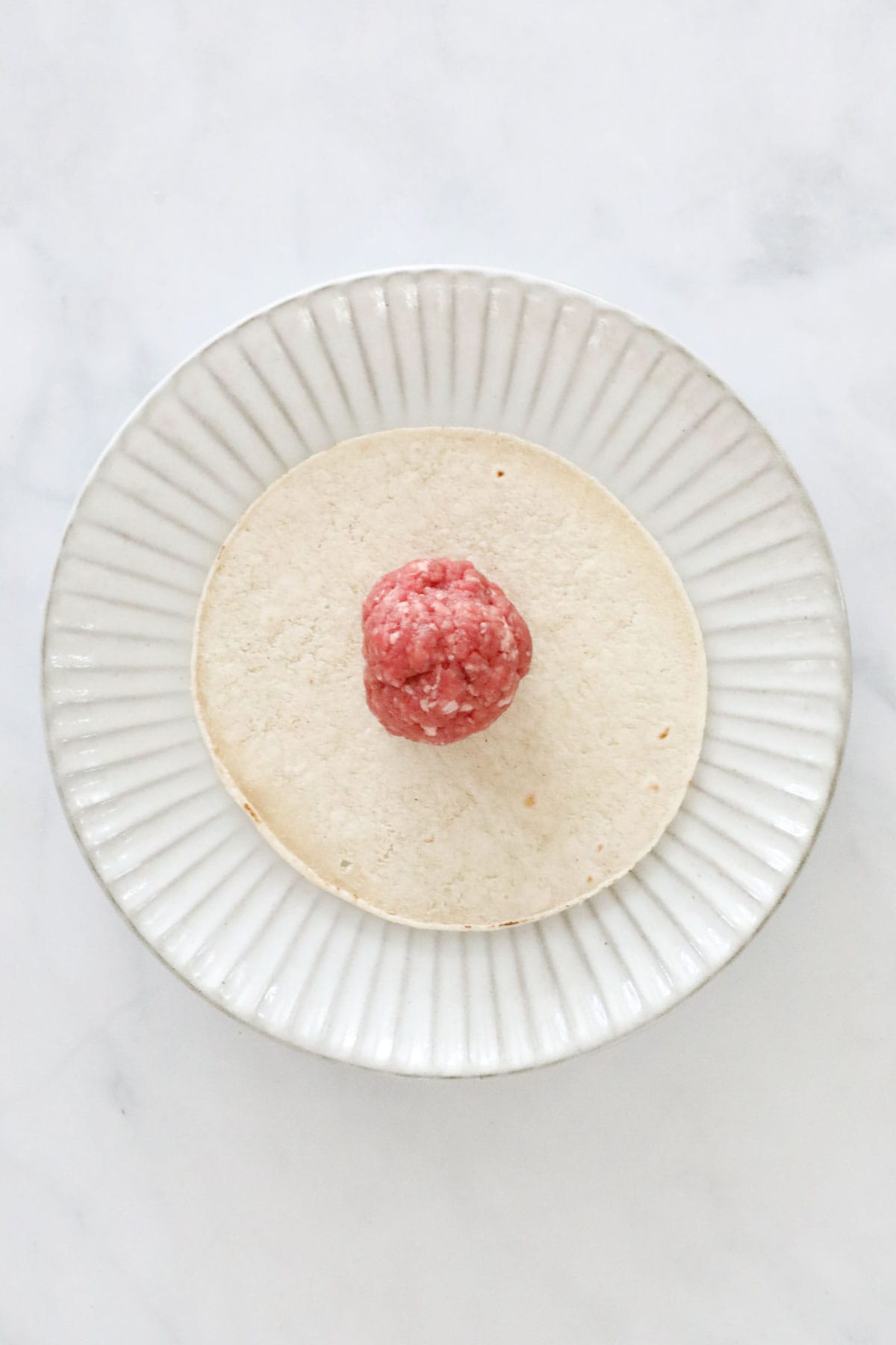 Beef mince ball on a small tortilla on a plate.