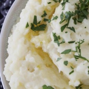 An overhead shot of a bowl of cauliflower and potato mash with parsley on top.