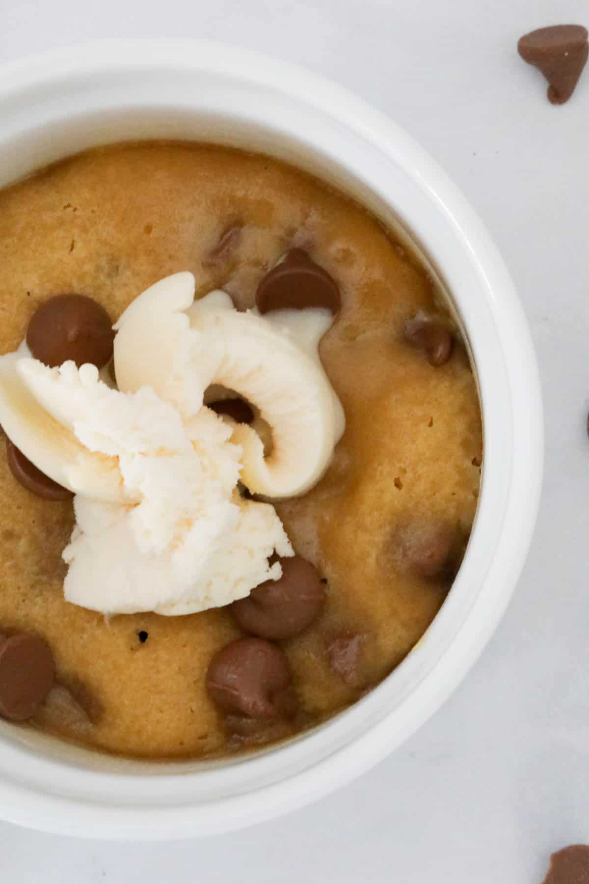 An overhead shot of a chocolate chip cookie in a white ramekin.