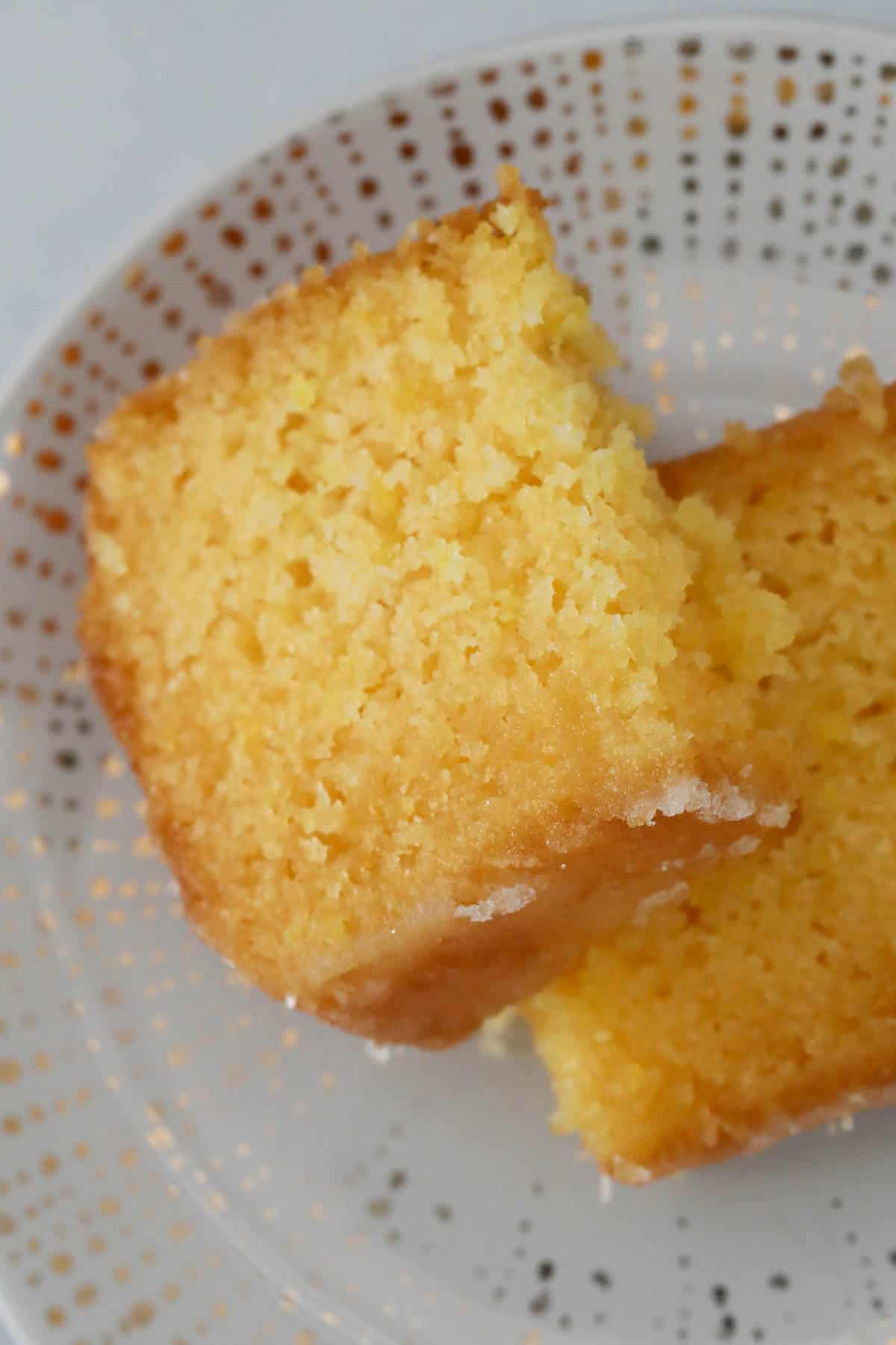 Close up of a slice of moist lemon drizzle cake on a plate.