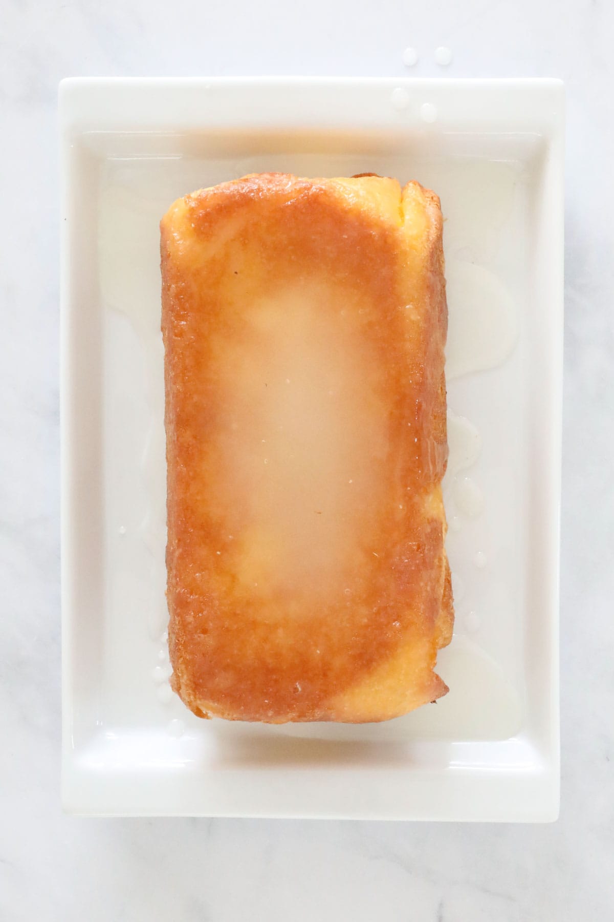 The lemon drizzle poured over the lemon loaf.