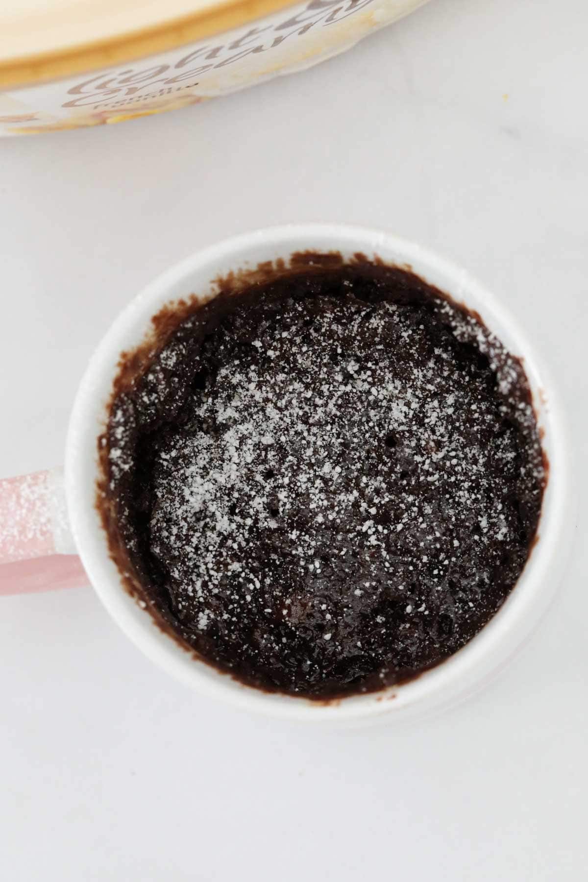 Overhead shot of a chocolate mug cake dusted with icing sugar.