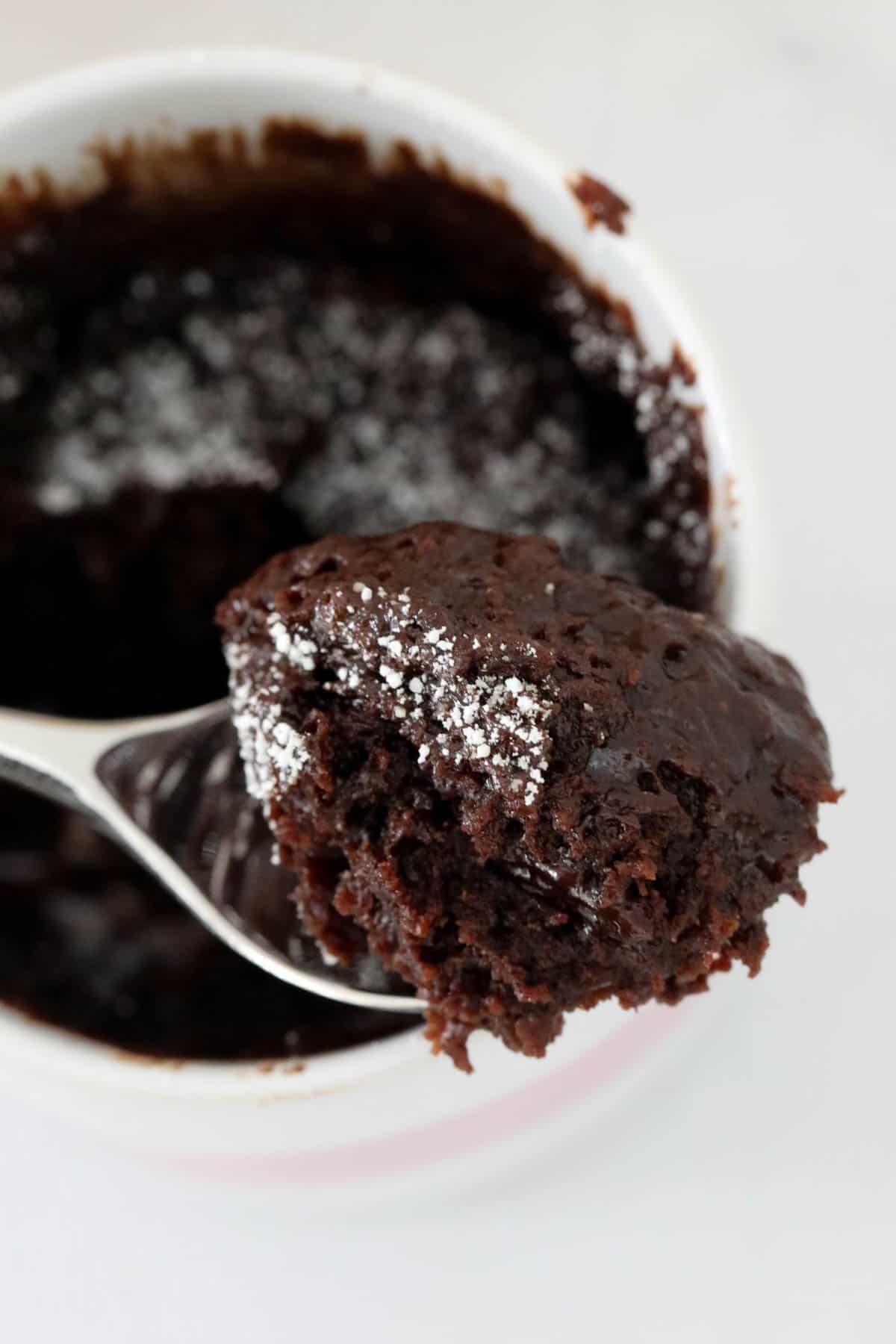 A spoon holding up some gooey gluten free chocolate cake.